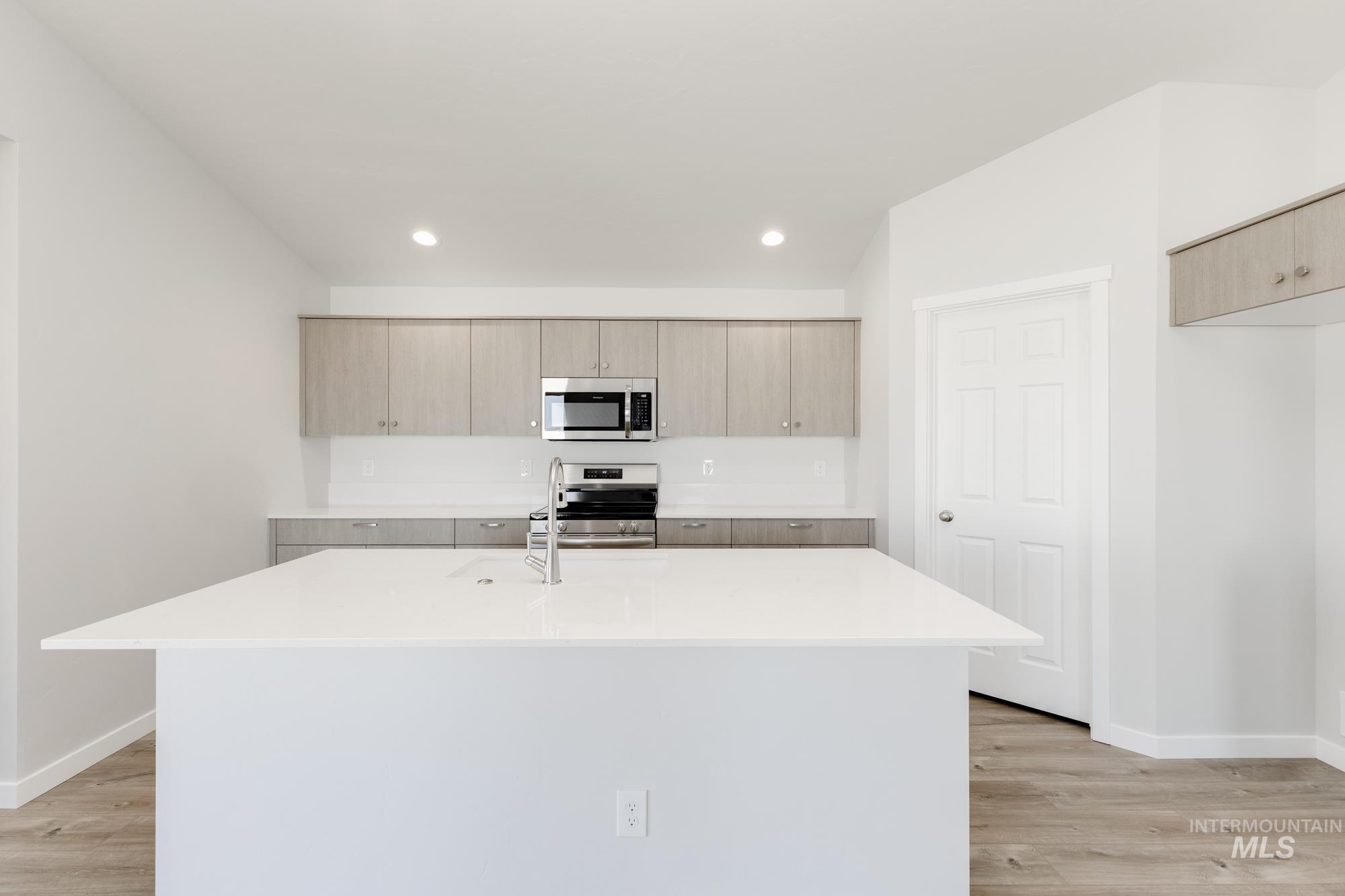 Kitchen featuring stainless steel appliances, light stone countertops, a kitchen island with sink, modern cabinets, and recessed lighting