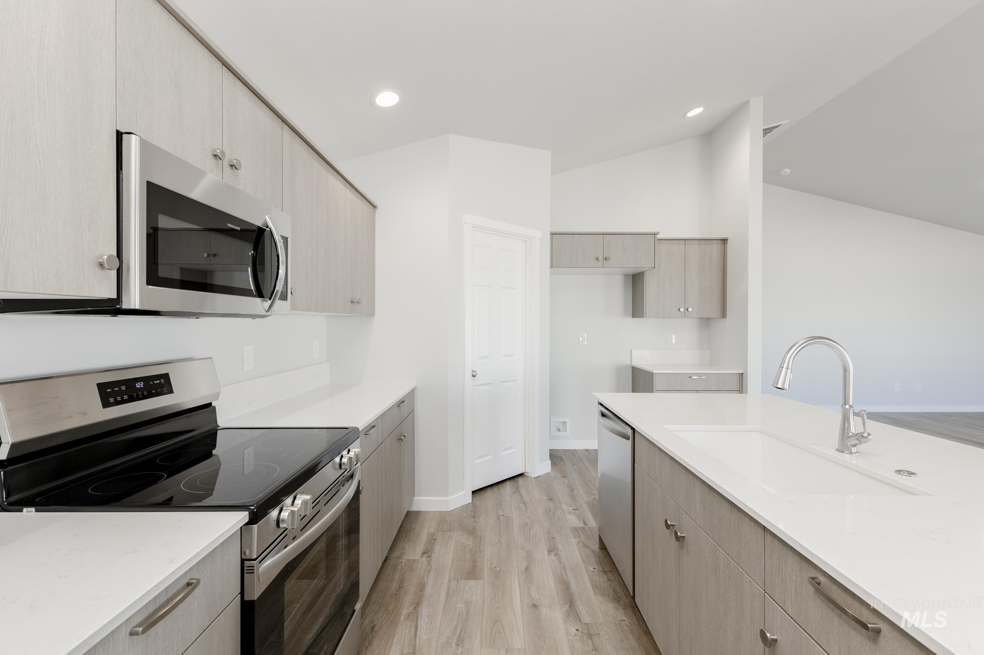 Kitchen featuring stainless steel appliances, light wood-style floors, light stone countertops, light brown cabinetry, and recessed lighting