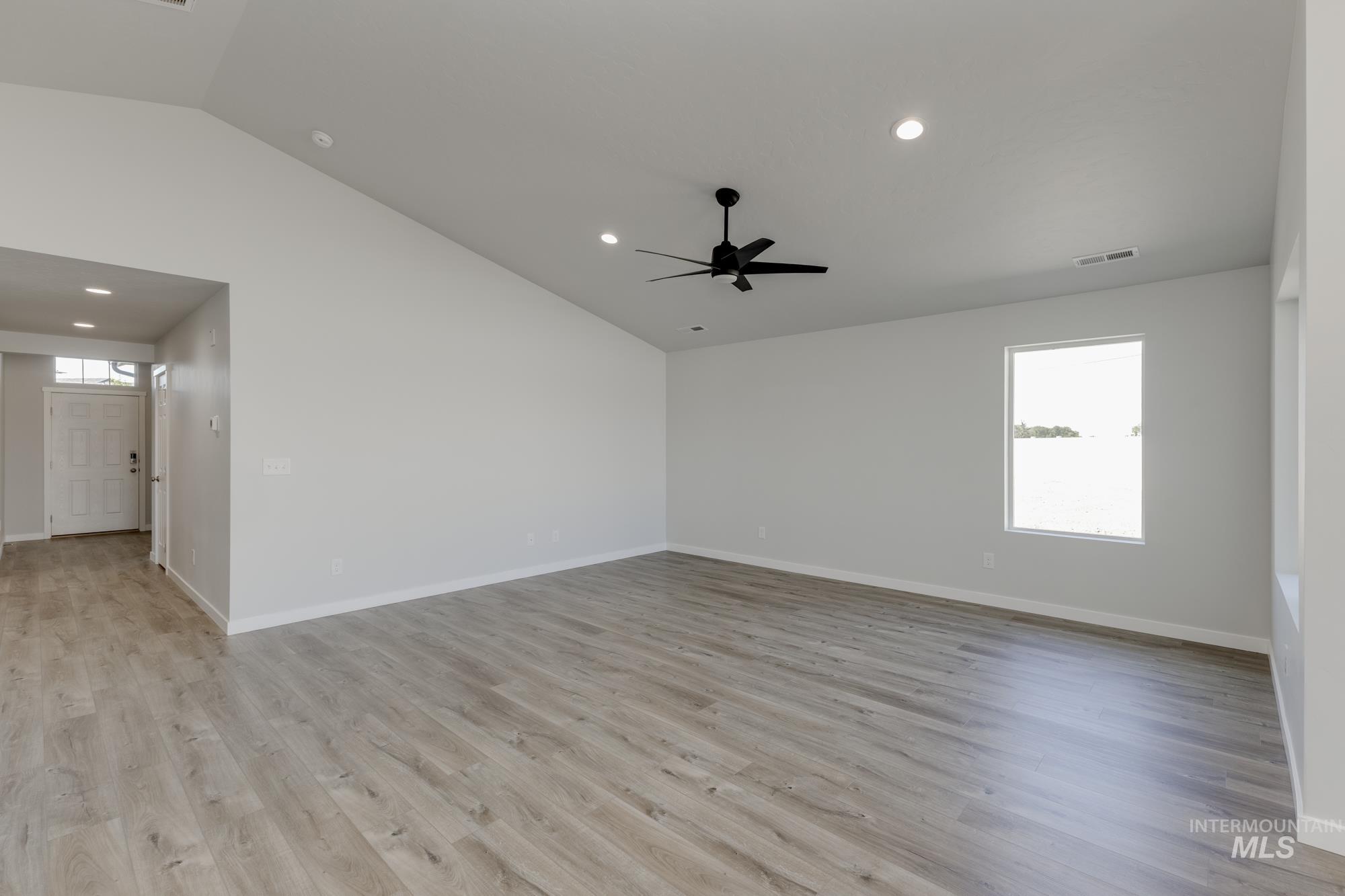 Spare room featuring vaulted ceiling, light wood finished floors, and recessed lighting