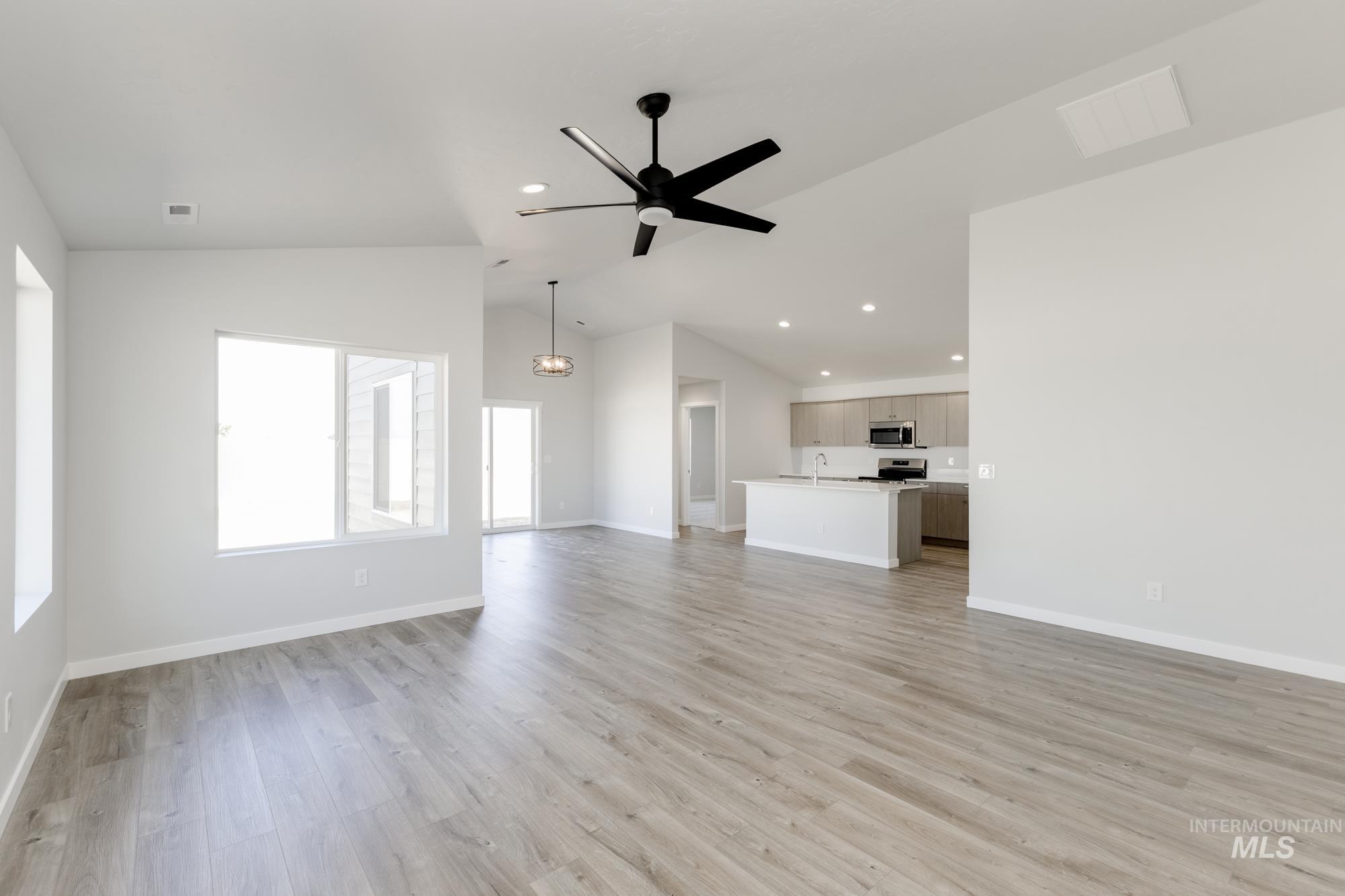 Unfurnished living room with light wood-style flooring, recessed lighting, ceiling fan, and high vaulted ceiling