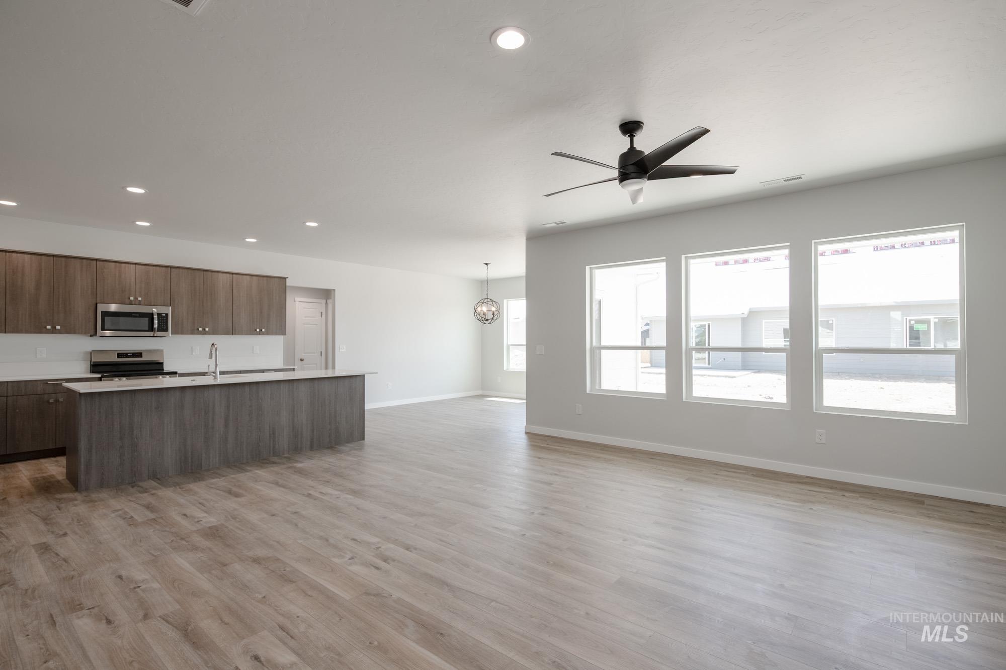Kitchen featuring appliances with stainless steel finishes, modern cabinets, open floor plan, light countertops, and recessed lighting