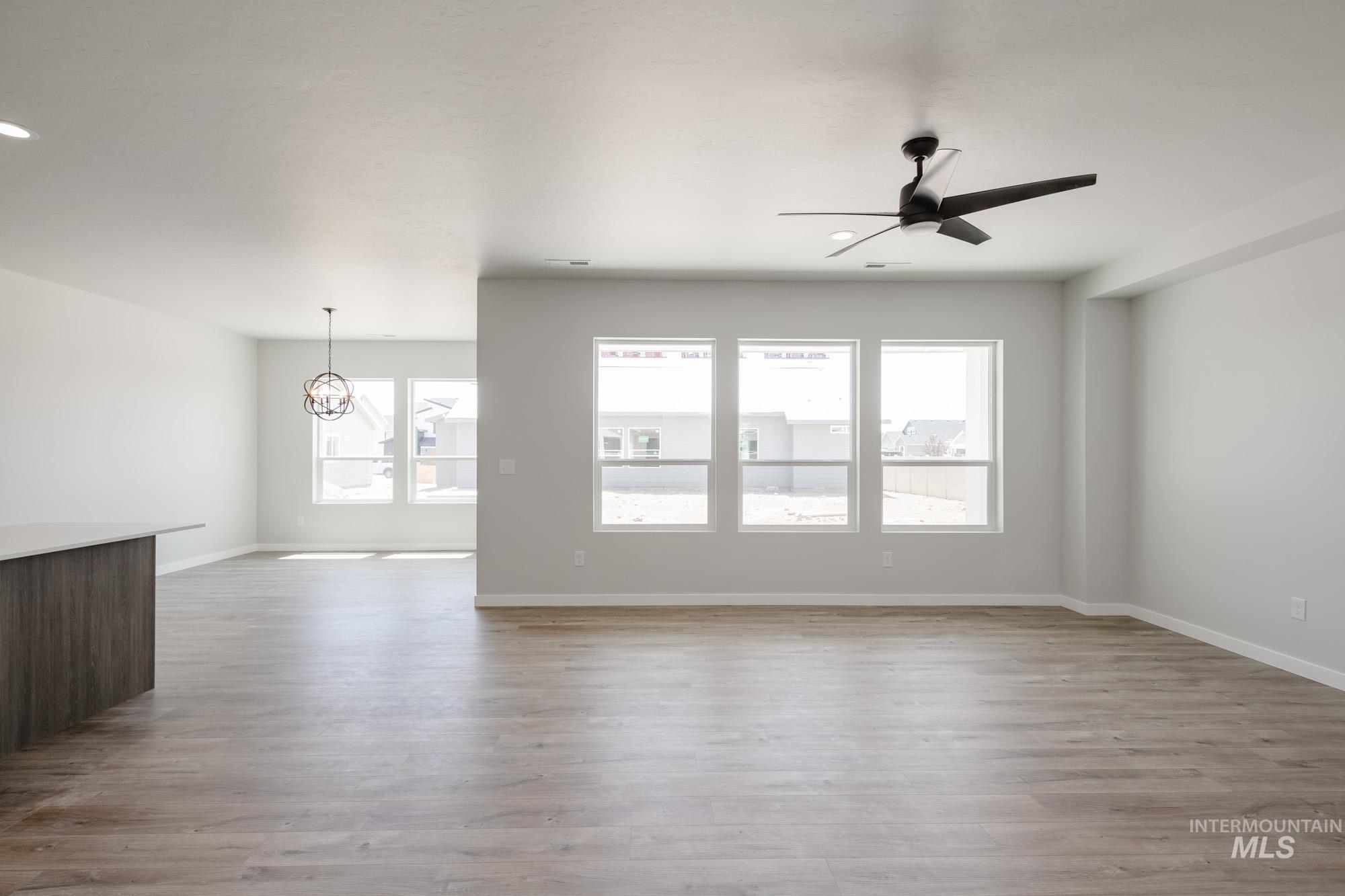 Spare room featuring a ceiling fan, a chandelier, wood finished floors, and recessed lighting