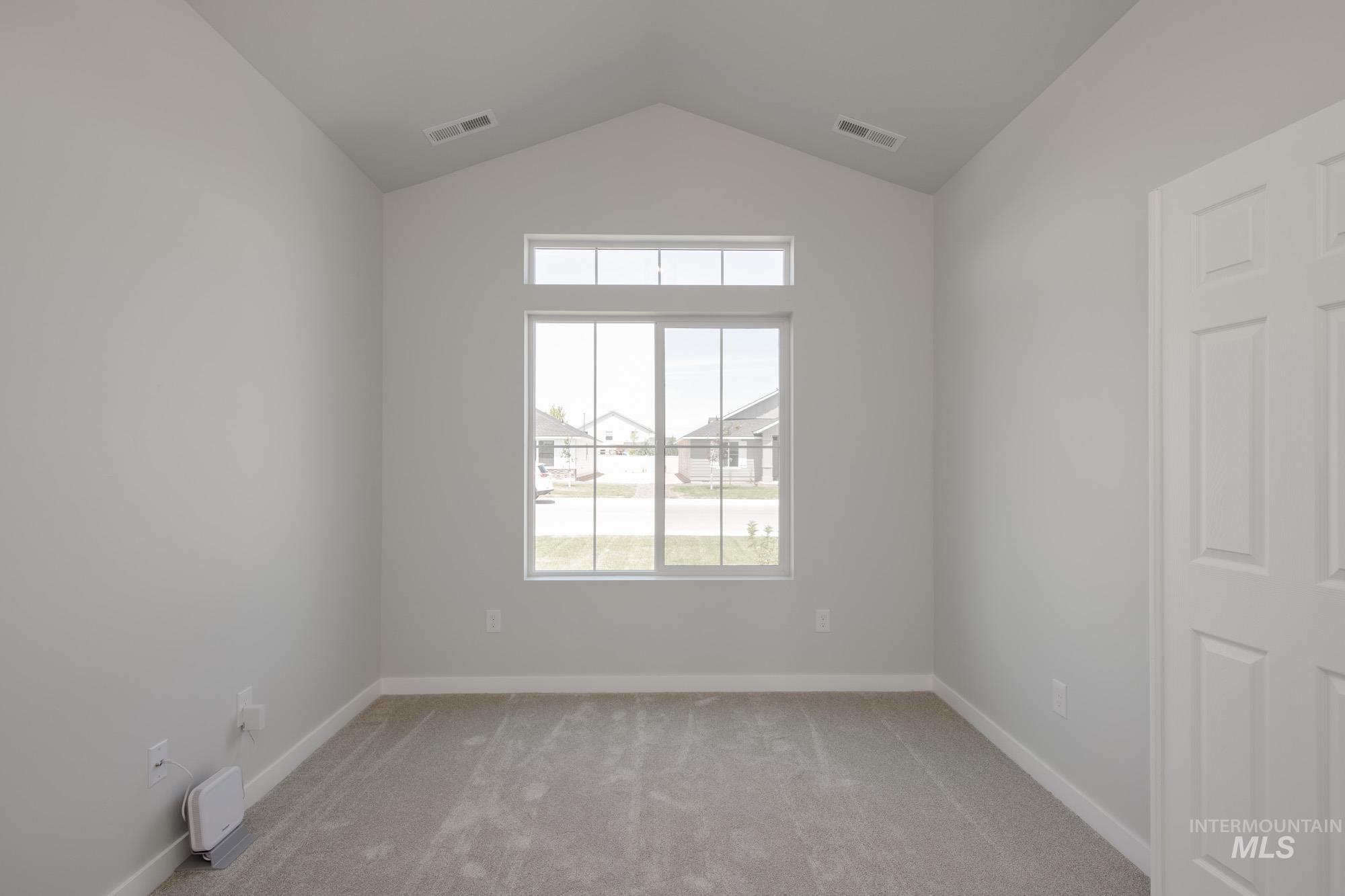 Spare room featuring lofted ceiling and light colored carpet