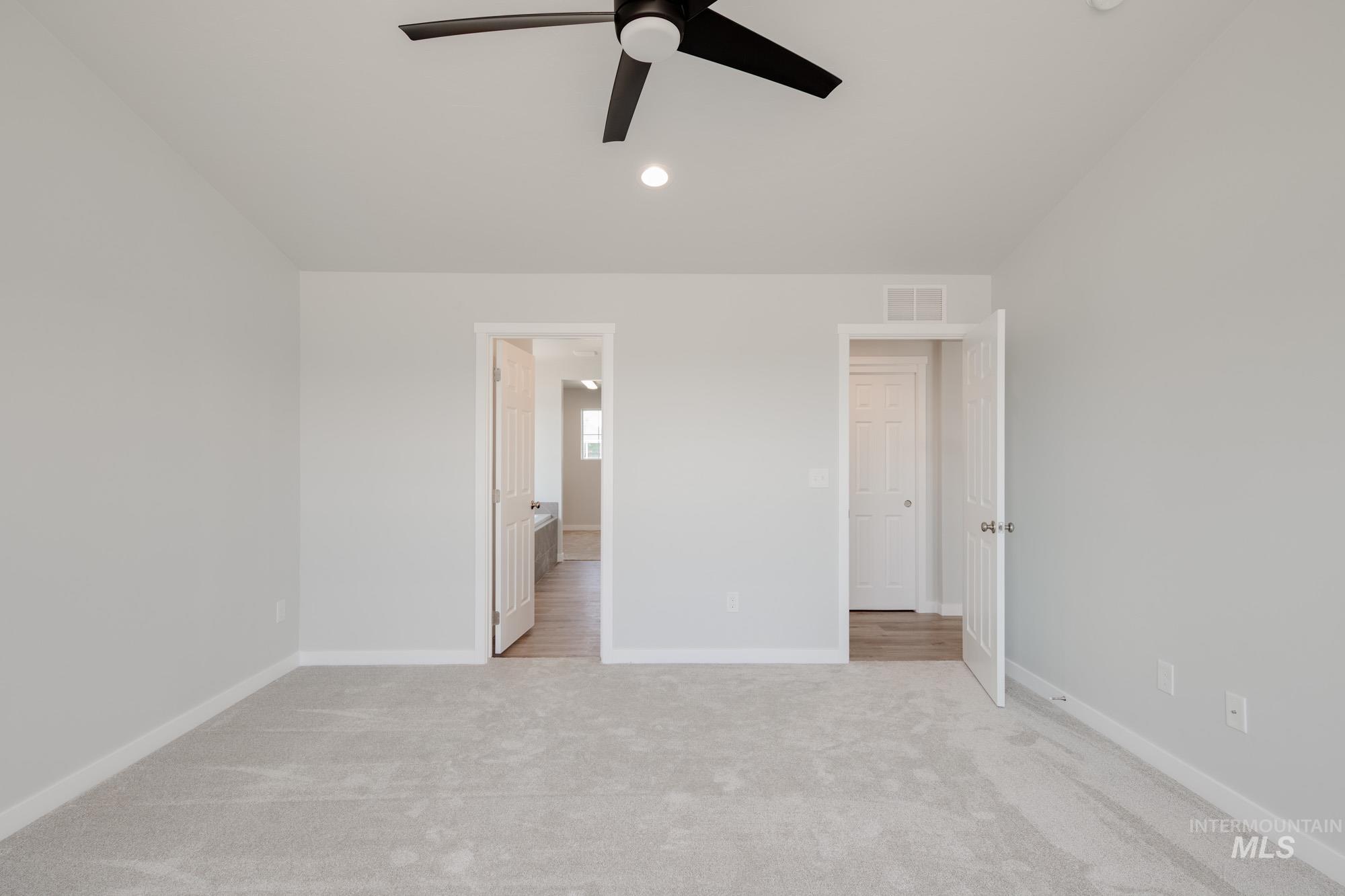 Unfurnished bedroom featuring light carpet, ensuite bath, a ceiling fan, and recessed lighting