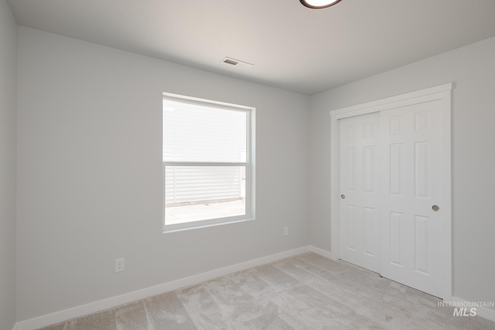 Unfurnished bedroom with light colored carpet and a closet