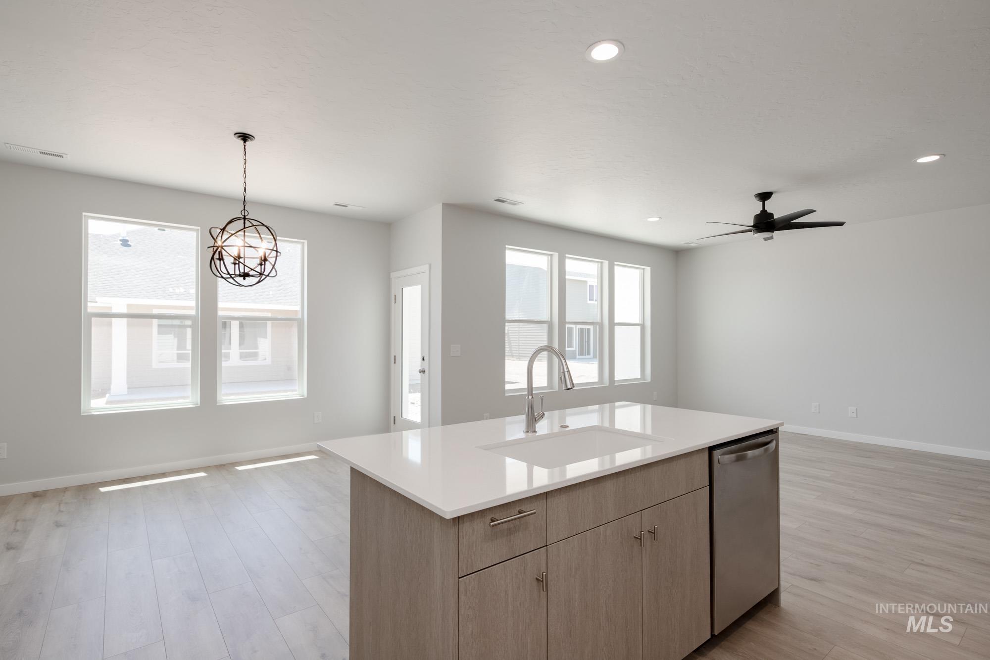 Kitchen with dishwasher, open floor plan, light wood-style flooring, light countertops, and hanging light fixtures