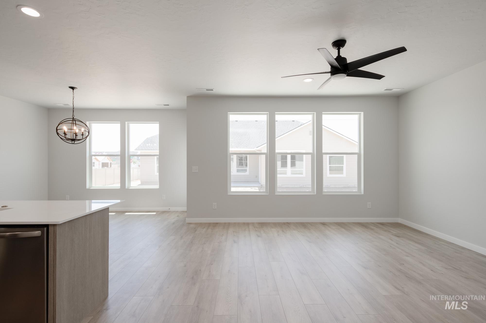 Unfurnished living room featuring a chandelier, a ceiling fan, light wood-style floors, and recessed lighting