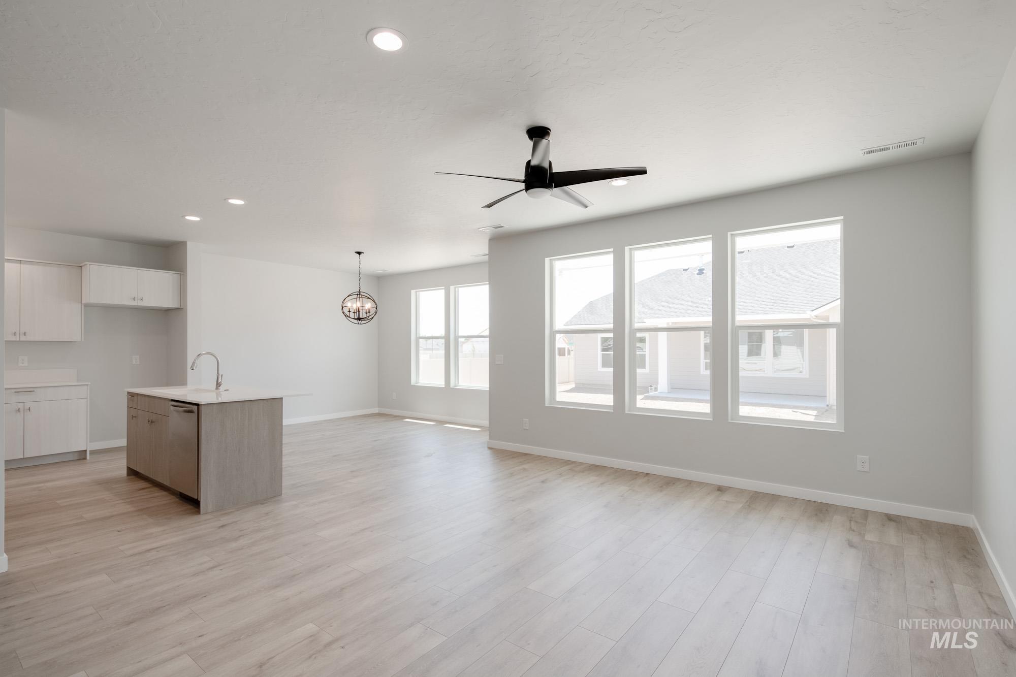 Unfurnished living room featuring a ceiling fan, recessed lighting, light wood-style flooring, and a chandelier