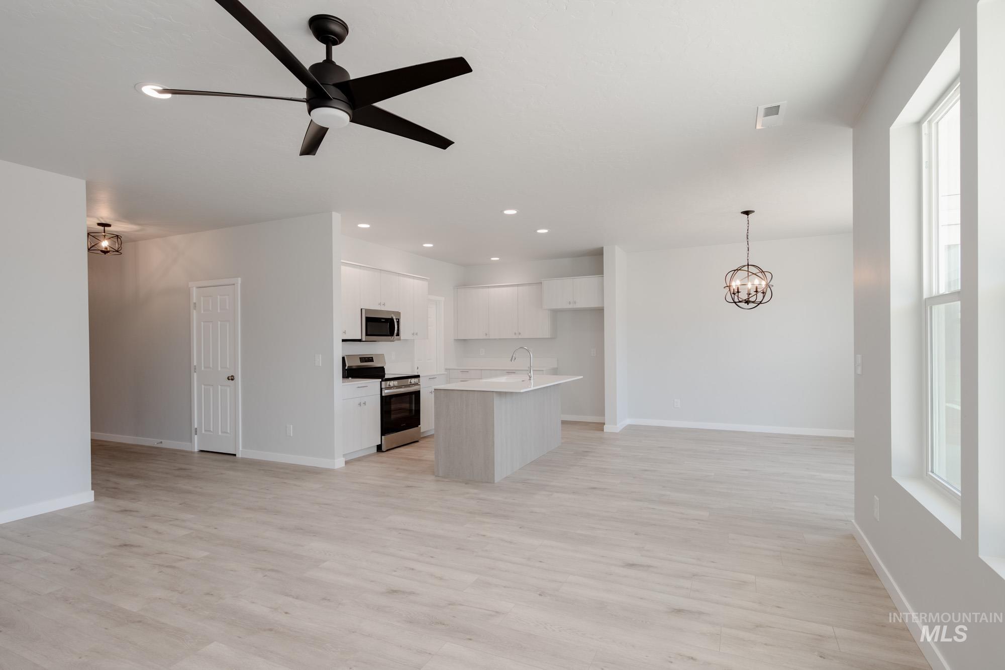 Kitchen with stainless steel appliances, open floor plan, a chandelier, ceiling fan, and recessed lighting