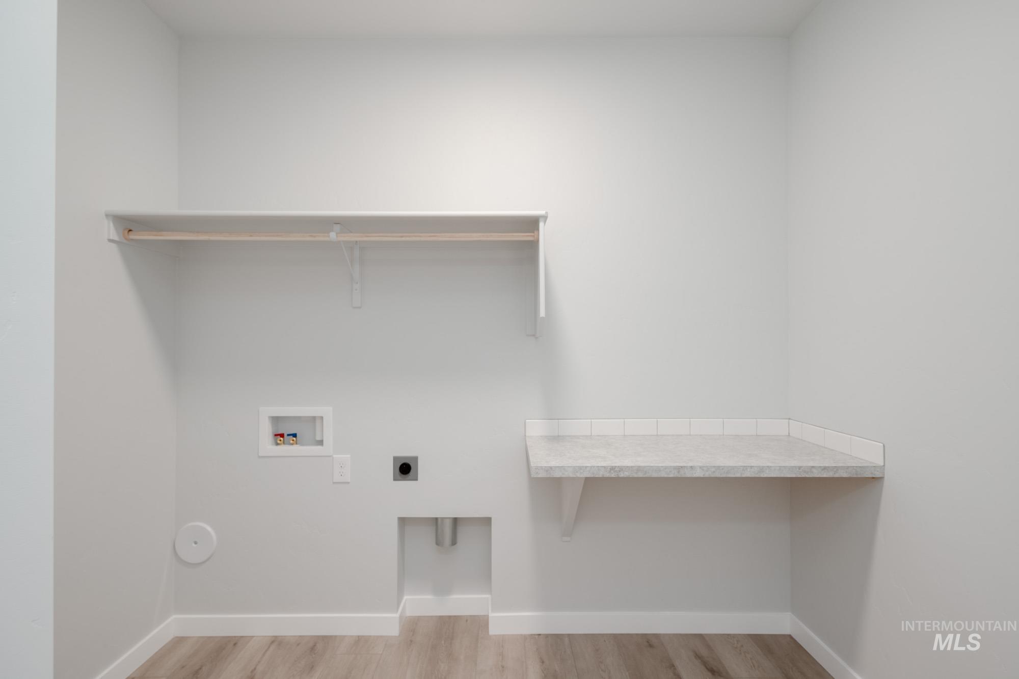 Washroom with light wood finished floors, washer hookup, hookup for an electric dryer, and a desk