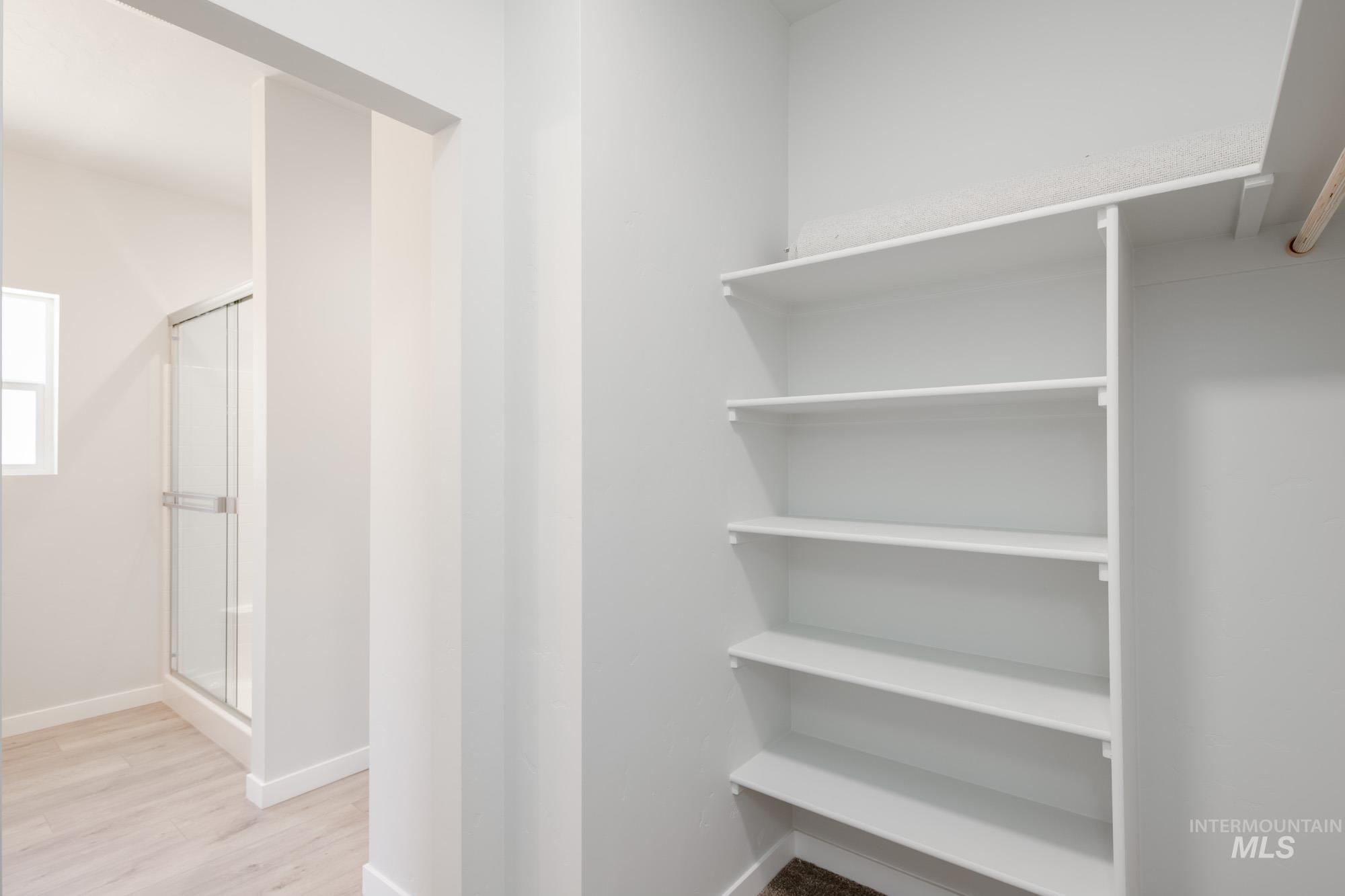 Walk in closet with light wood-style floors