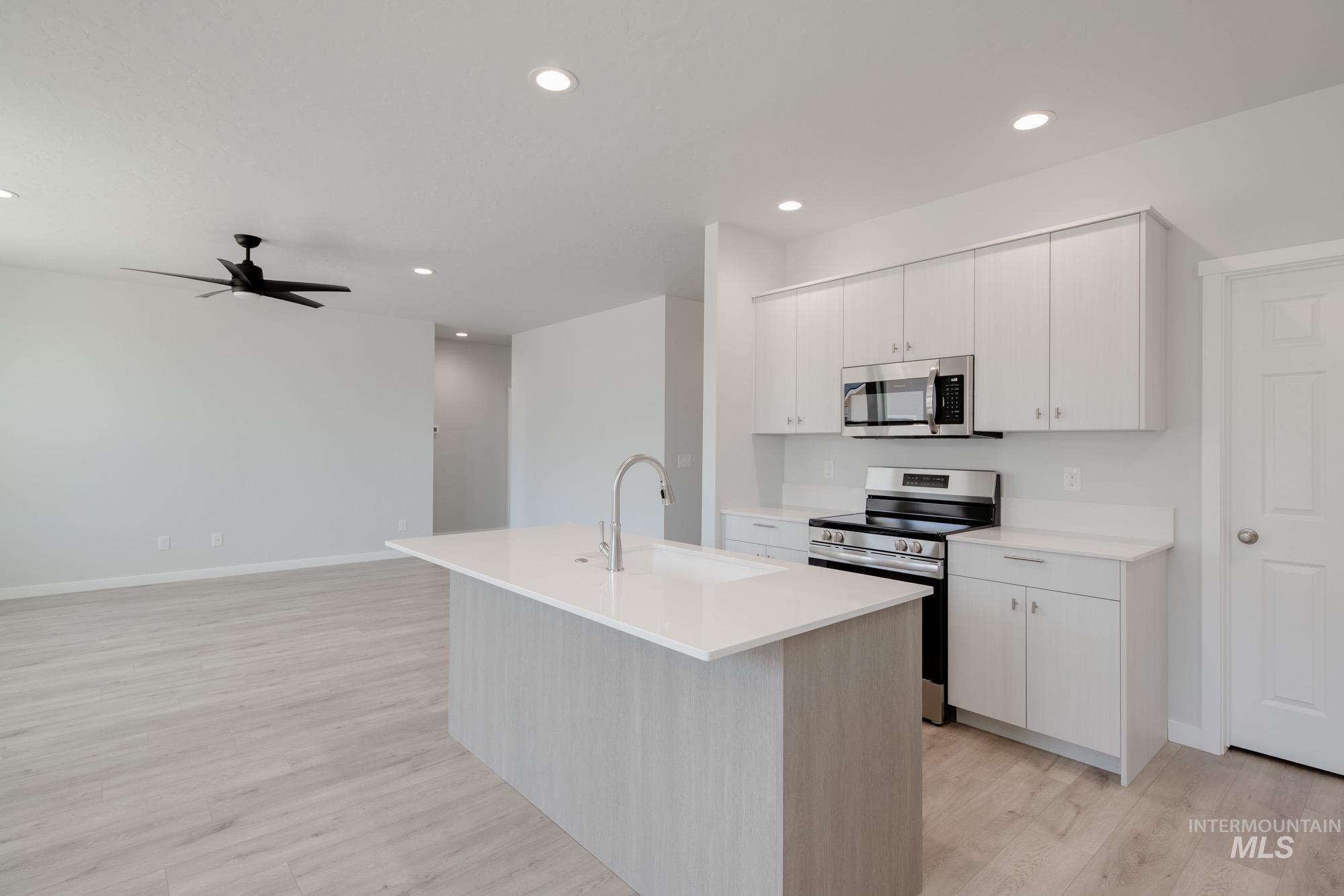 Kitchen featuring stainless steel appliances, light wood-style floors, recessed lighting, light countertops, and a ceiling fan
