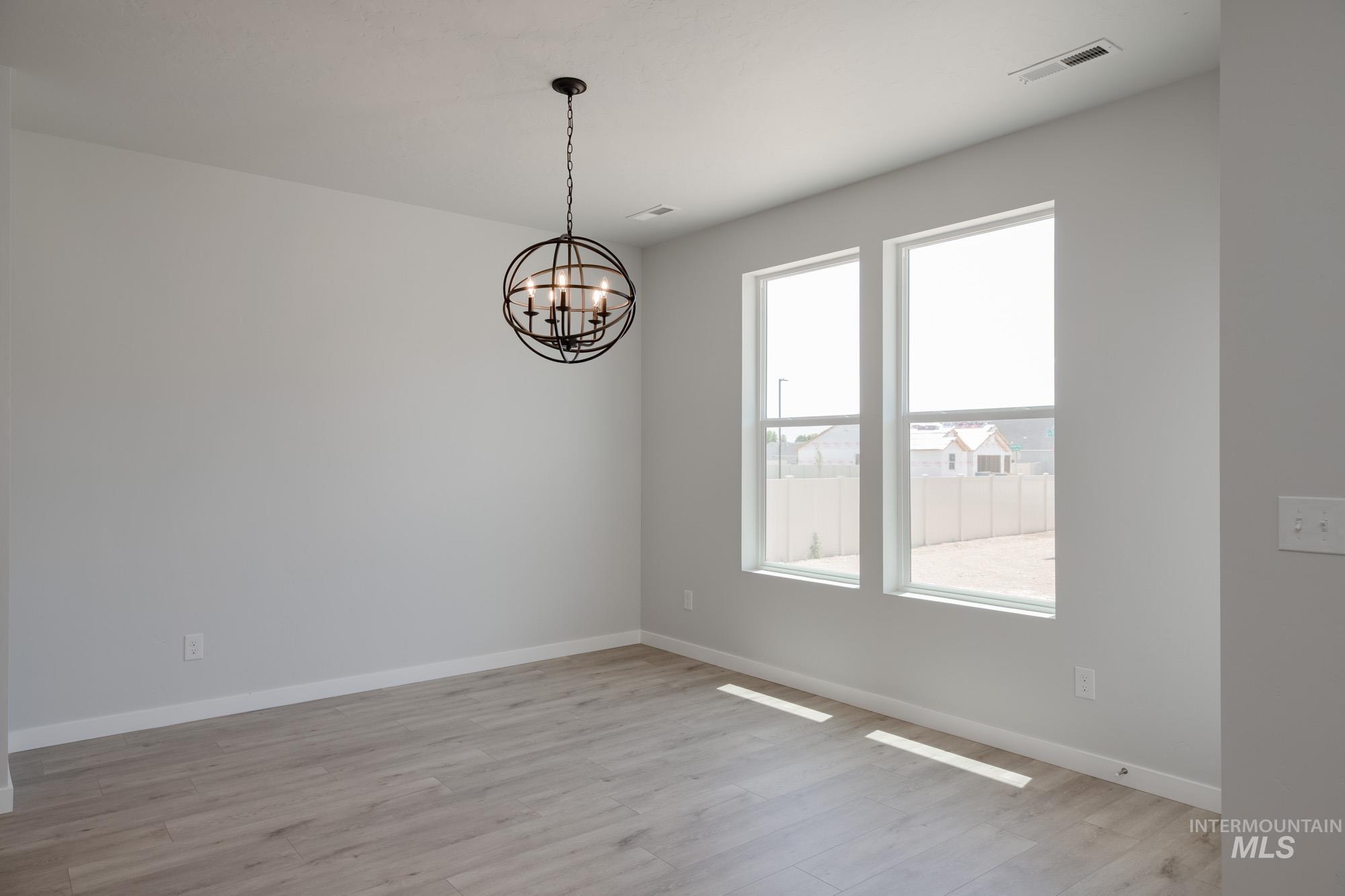 Spare room with light wood-type flooring and a chandelier