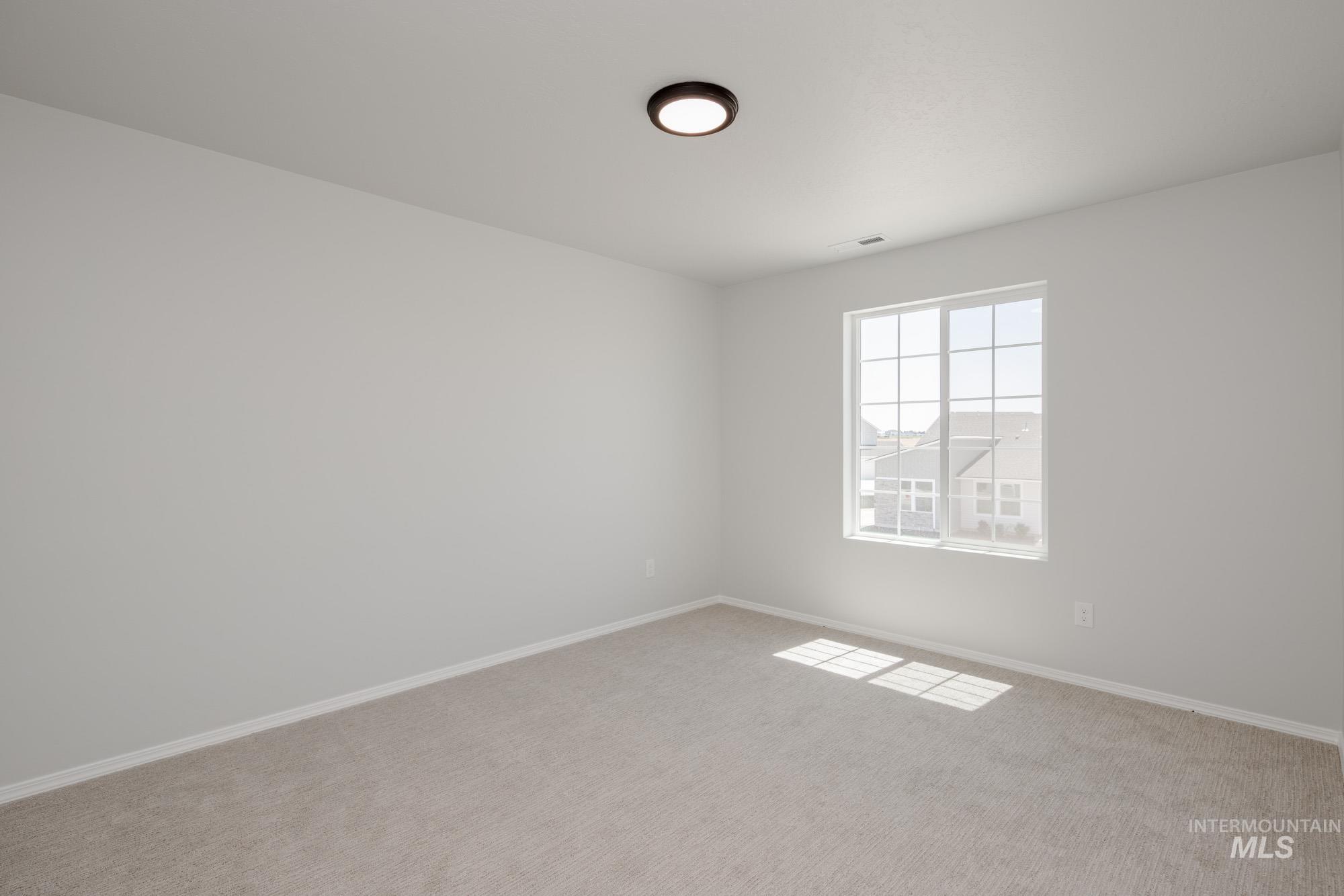Carpeted spare room featuring baseboards