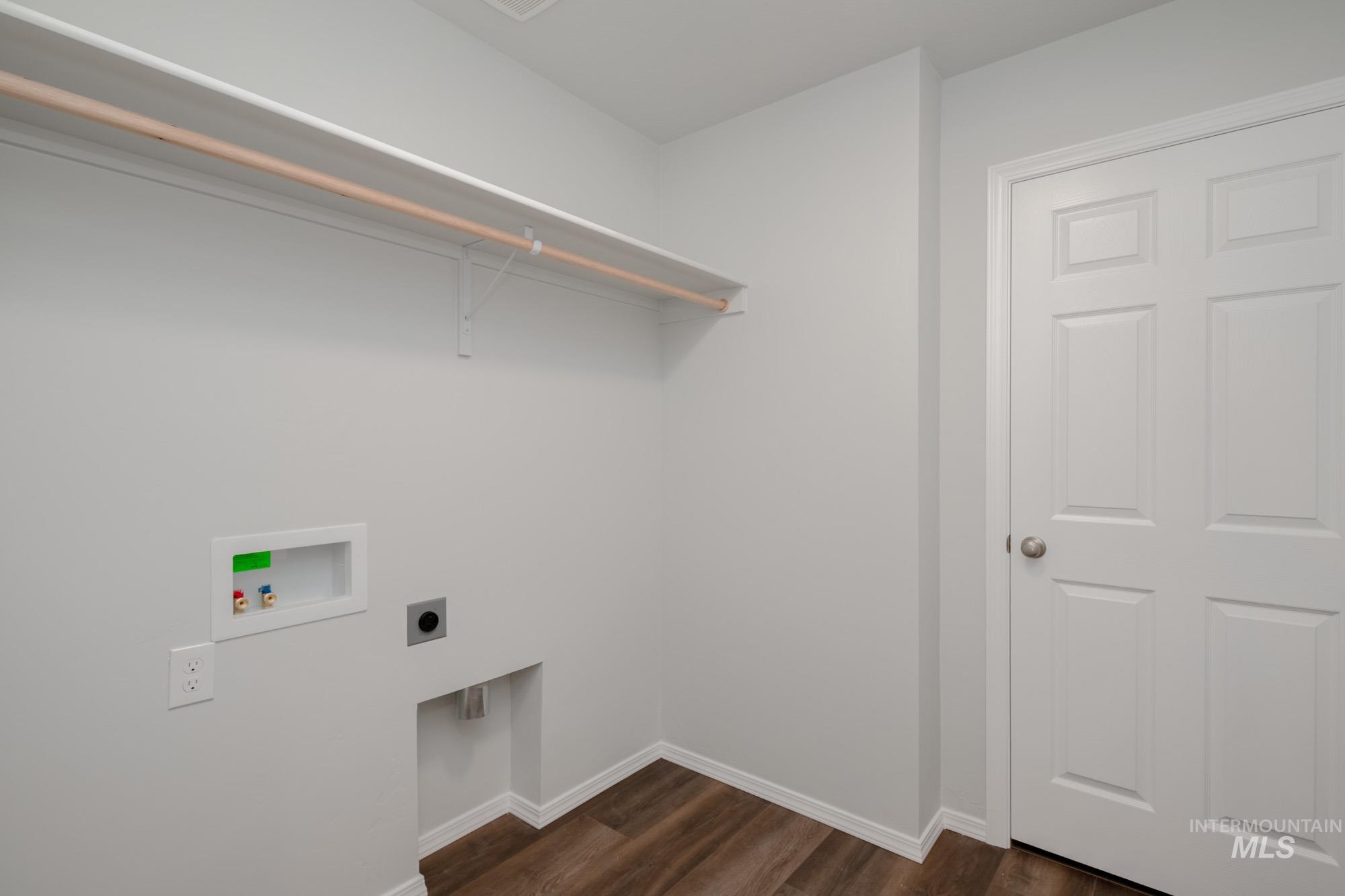 Washroom with electric dryer hookup, hookup for a washing machine, and dark wood finished floors