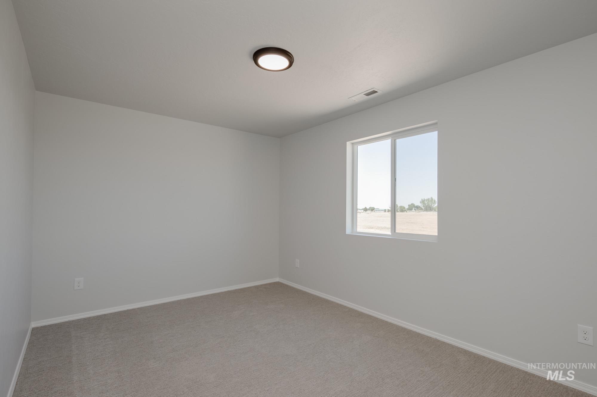 Spare room with baseboards and light colored carpet
