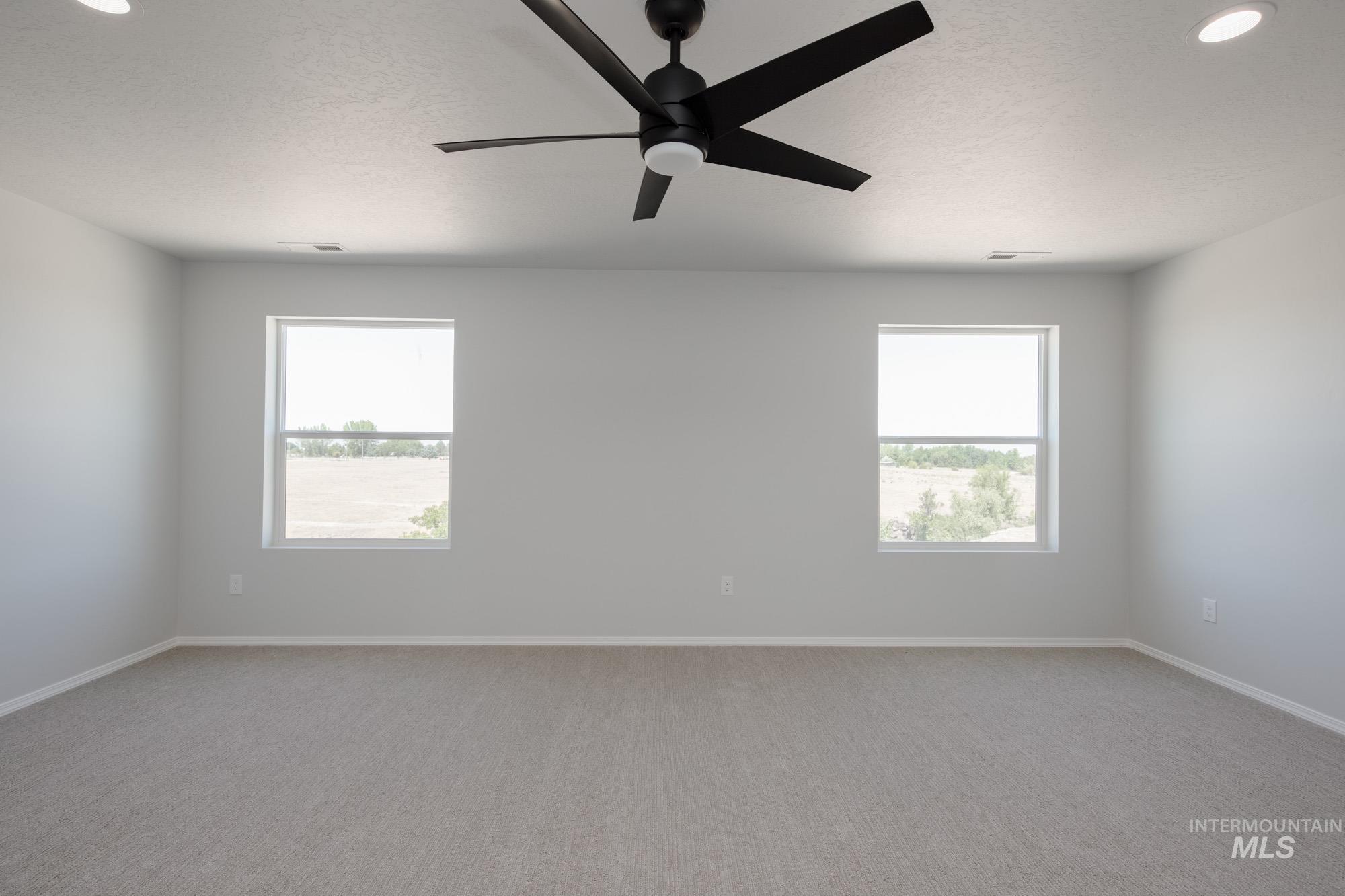 Carpeted spare room with ceiling fan and a textured ceiling