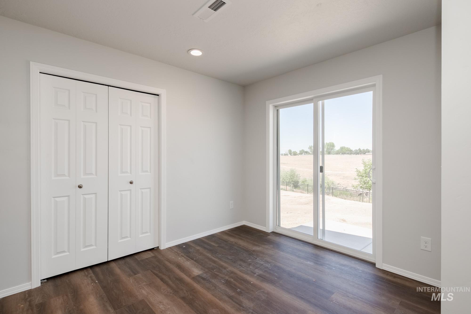 Unfurnished bedroom with access to outside, dark wood-style flooring, a closet, and recessed lighting