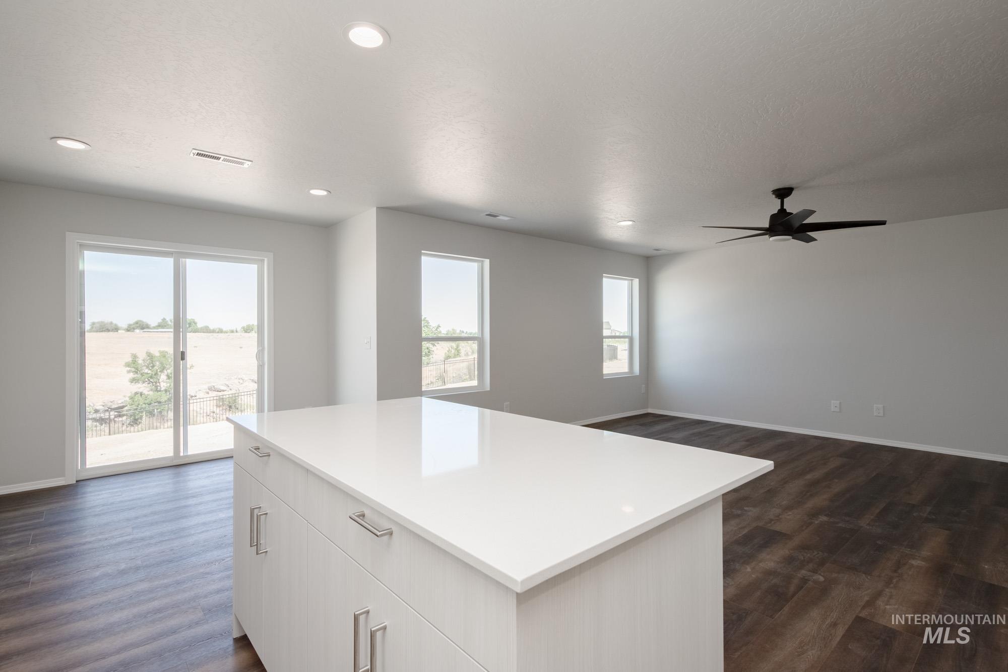 Kitchen with dark wood finished floors, a center island, light countertops, ceiling fan, and recessed lighting