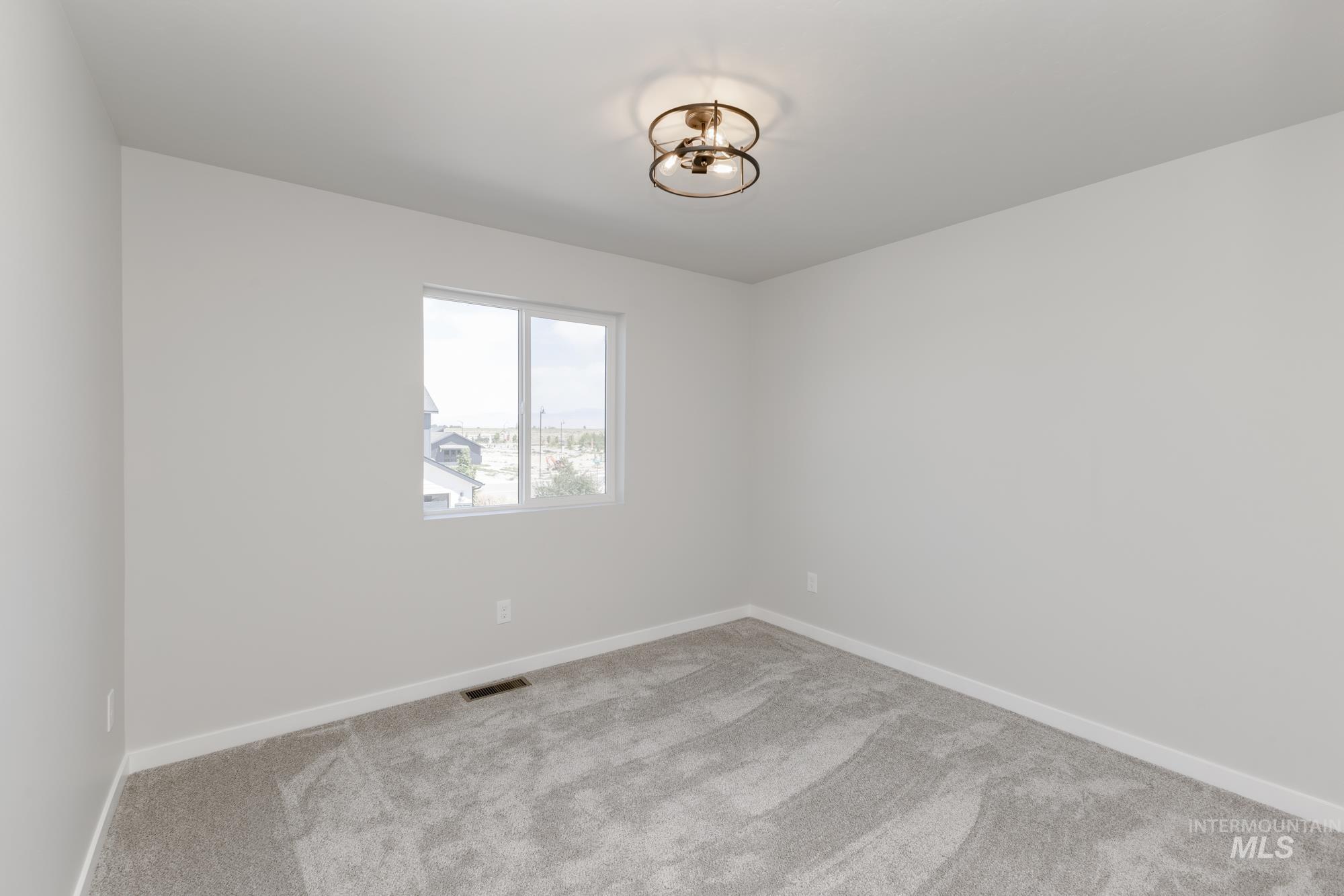 Carpeted spare room featuring baseboards