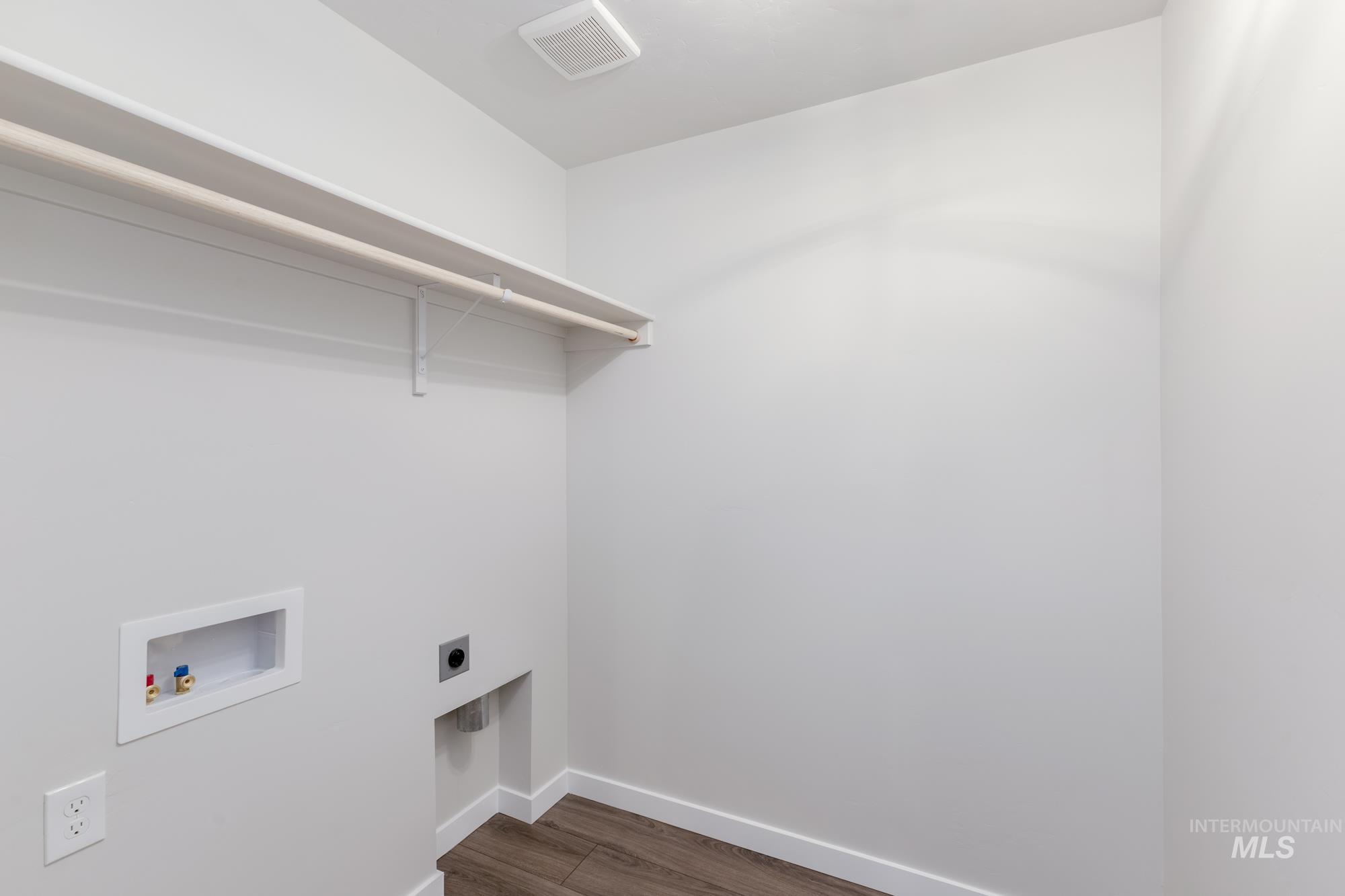 Washroom with electric dryer hookup, hookup for a washing machine, and dark wood-style floors