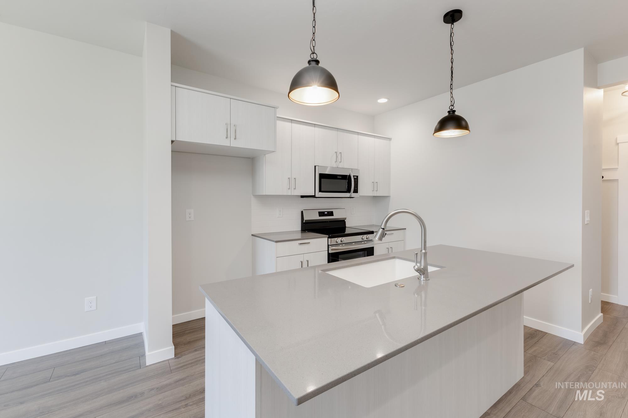 Kitchen with appliances with stainless steel finishes, light wood-style flooring, white cabinetry, and recessed lighting