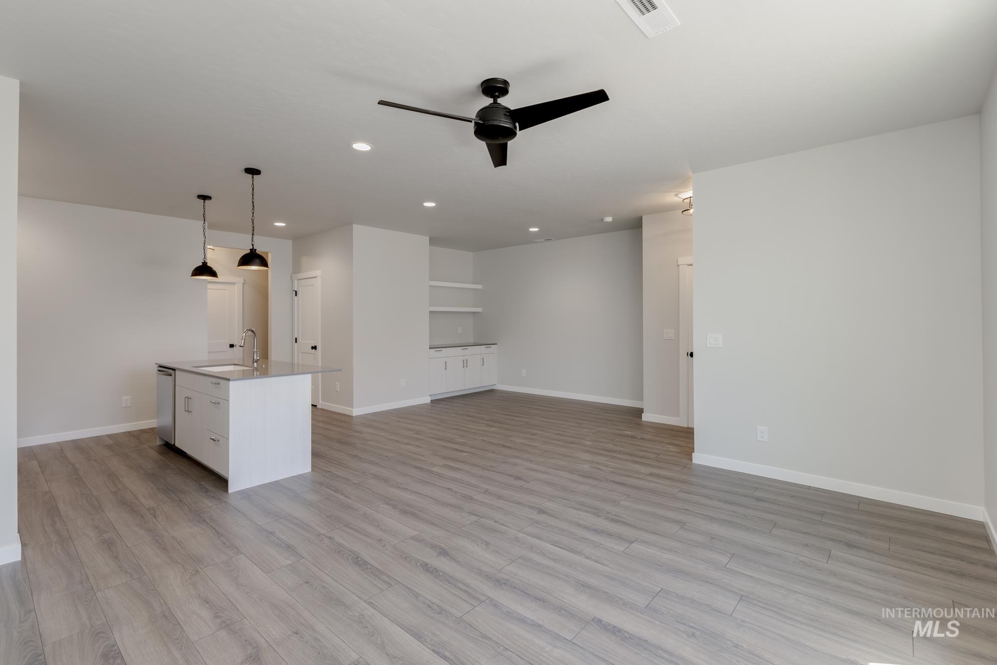 Unfurnished living room featuring light wood-style floors, a ceiling fan, and recessed lighting