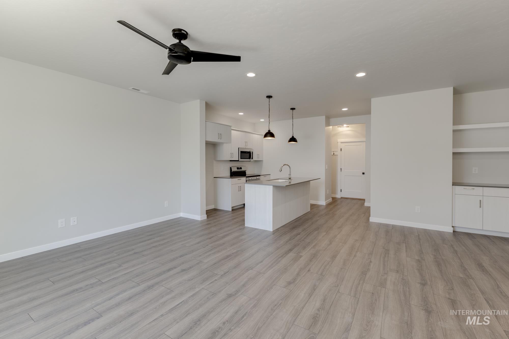 Unfurnished living room featuring a ceiling fan, light wood finished floors, and recessed lighting