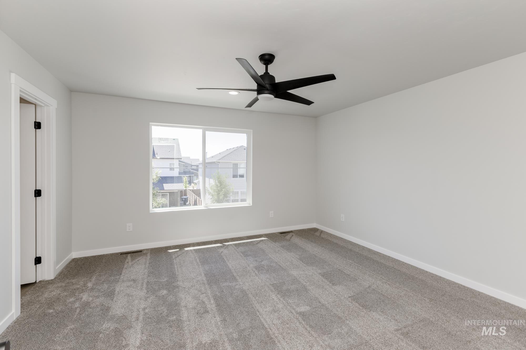 Carpeted empty room with baseboards and ceiling fan