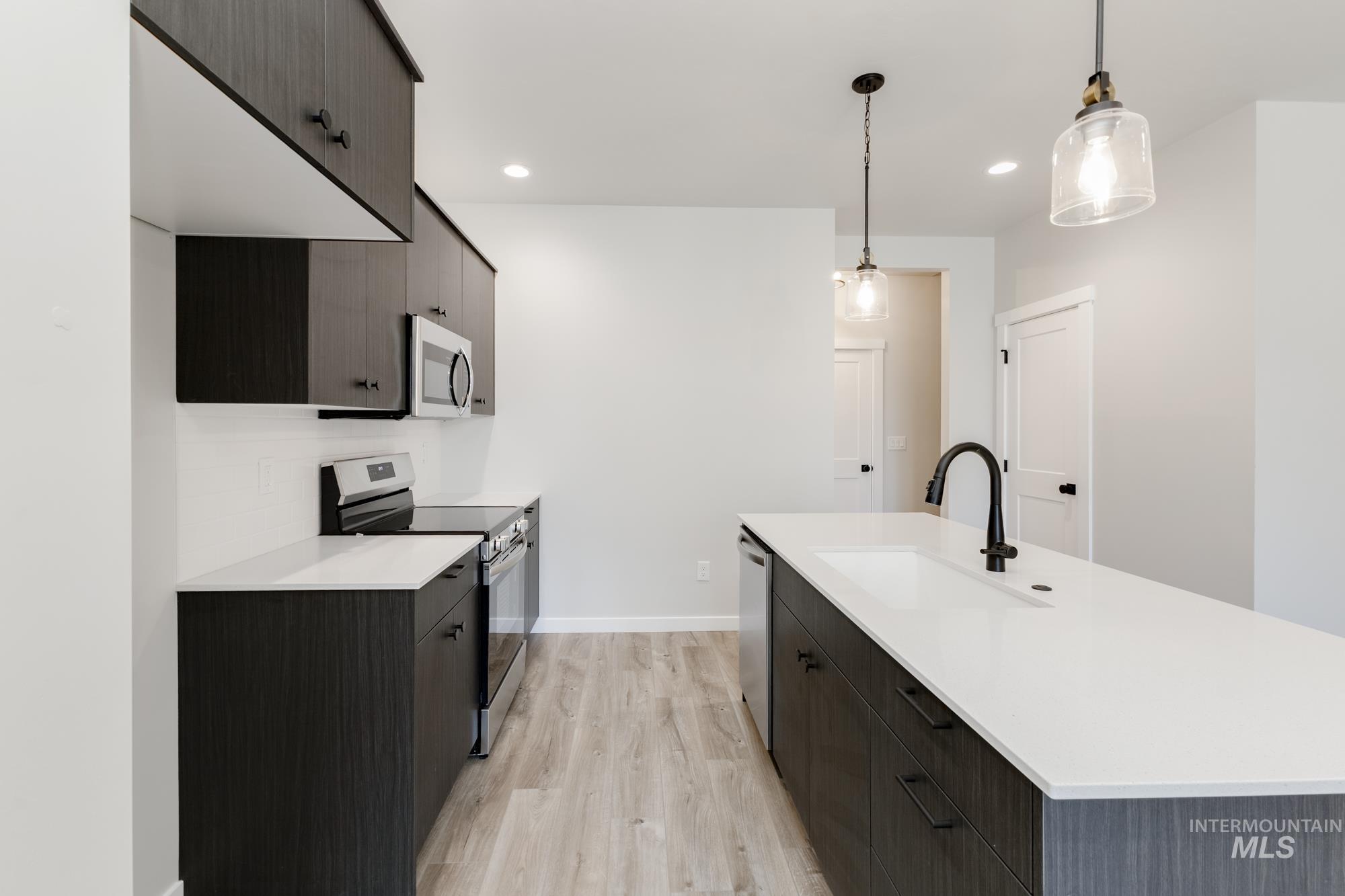 Kitchen featuring appliances with stainless steel finishes, light wood finished floors, light countertops, modern cabinets, and recessed lighting