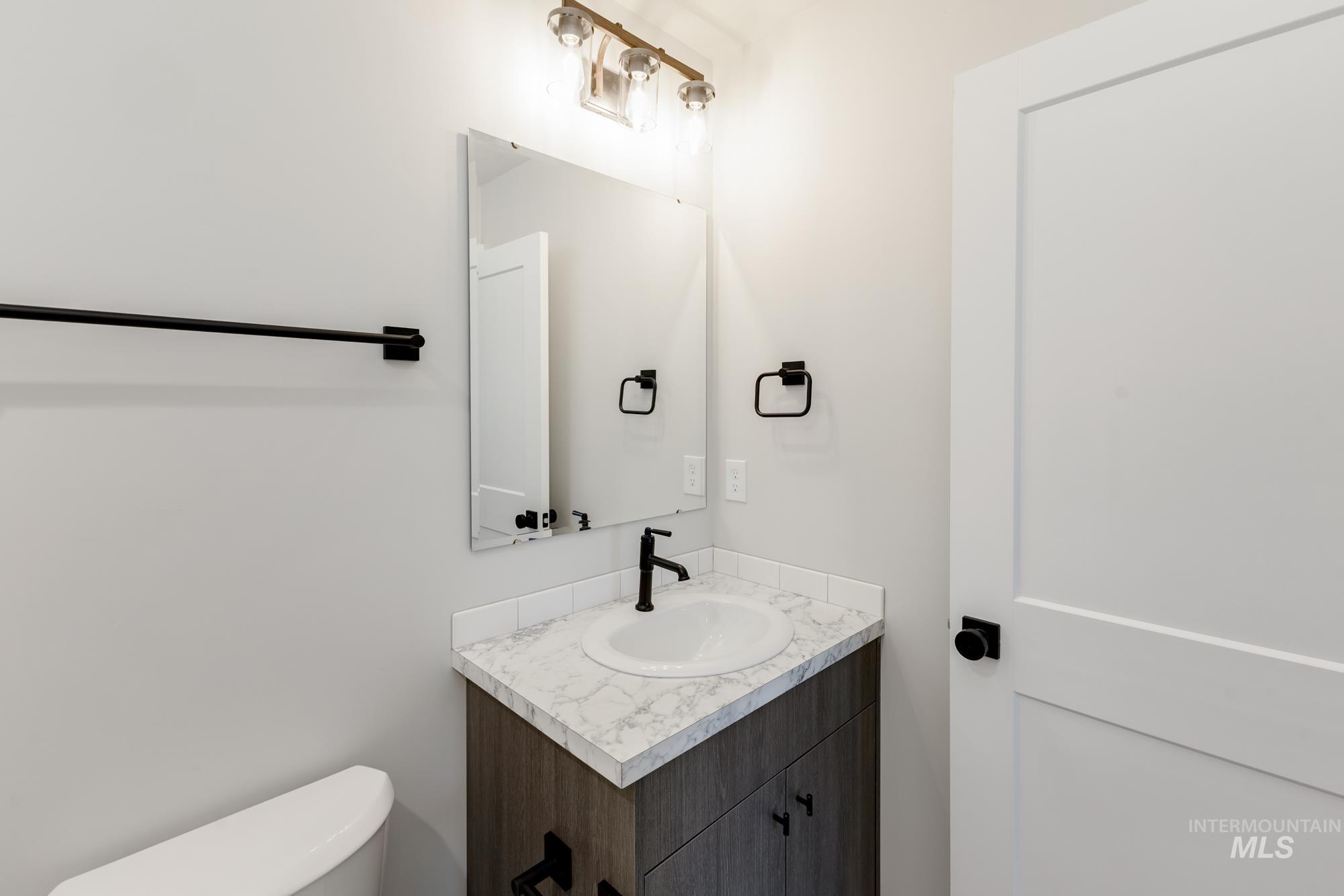 Half bathroom featuring vanity and toilet