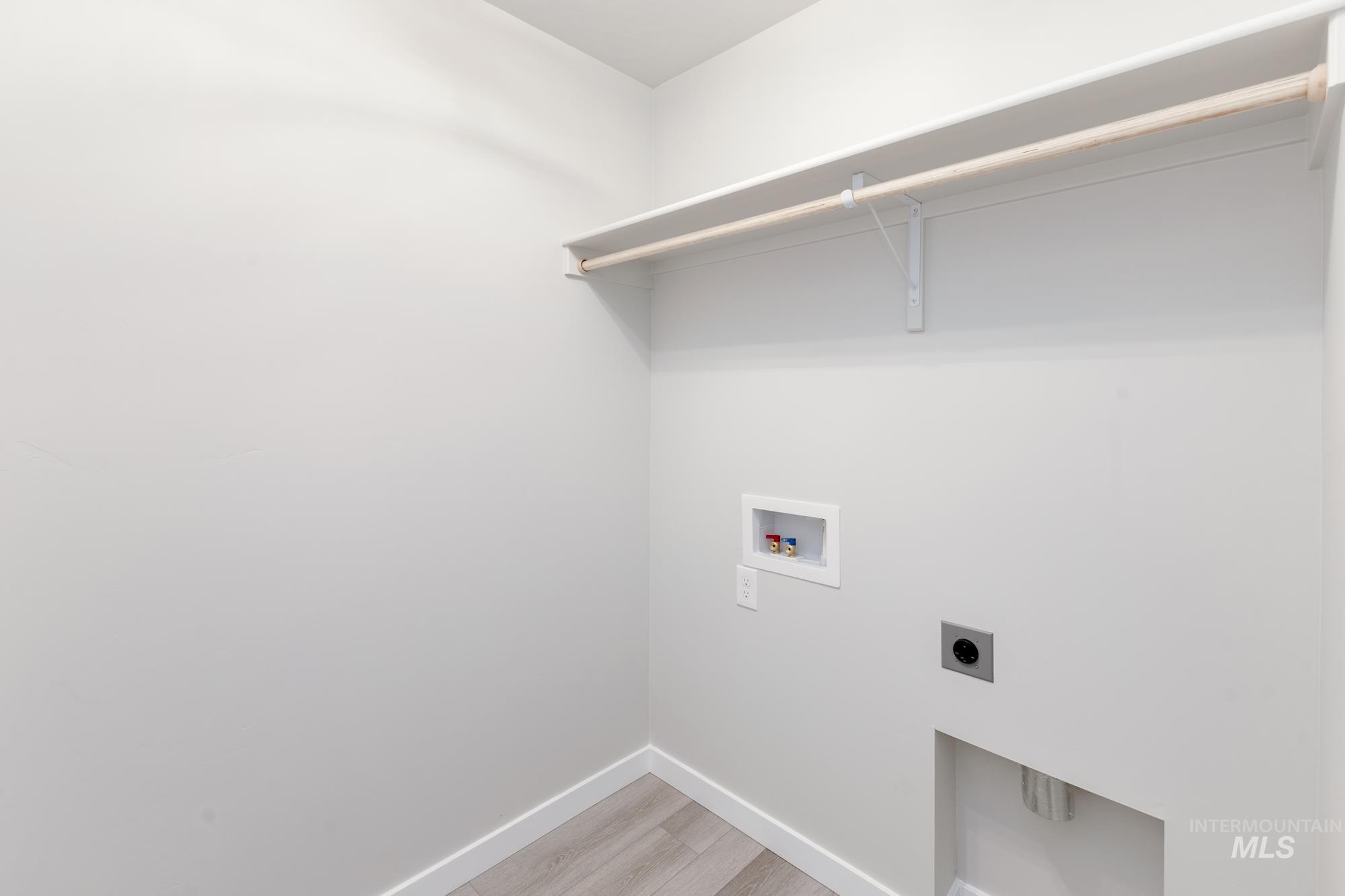 Laundry room with light wood-style floors, hookup for a washing machine, and electric dryer hookup