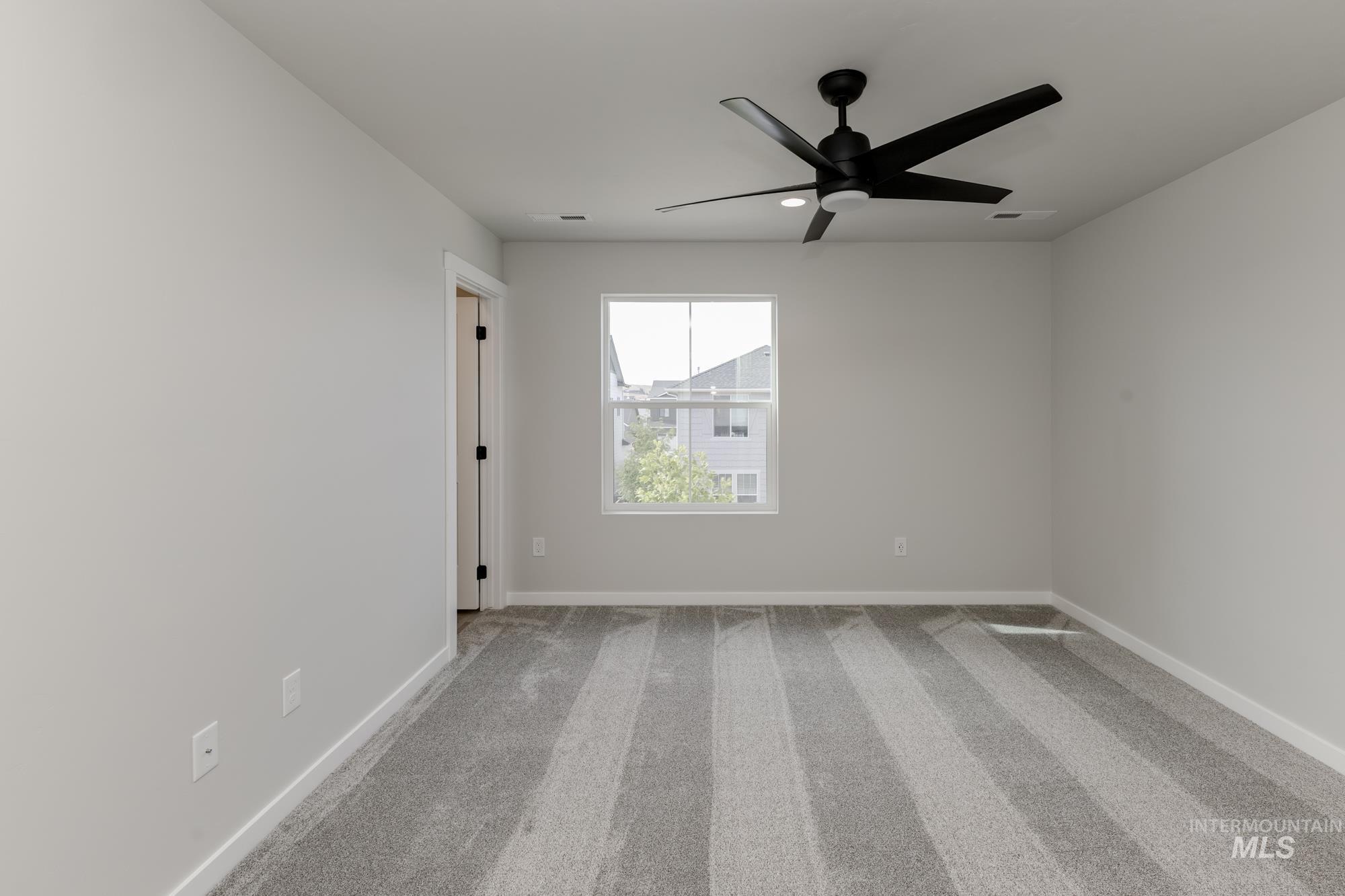 Spare room featuring light colored carpet and ceiling fan