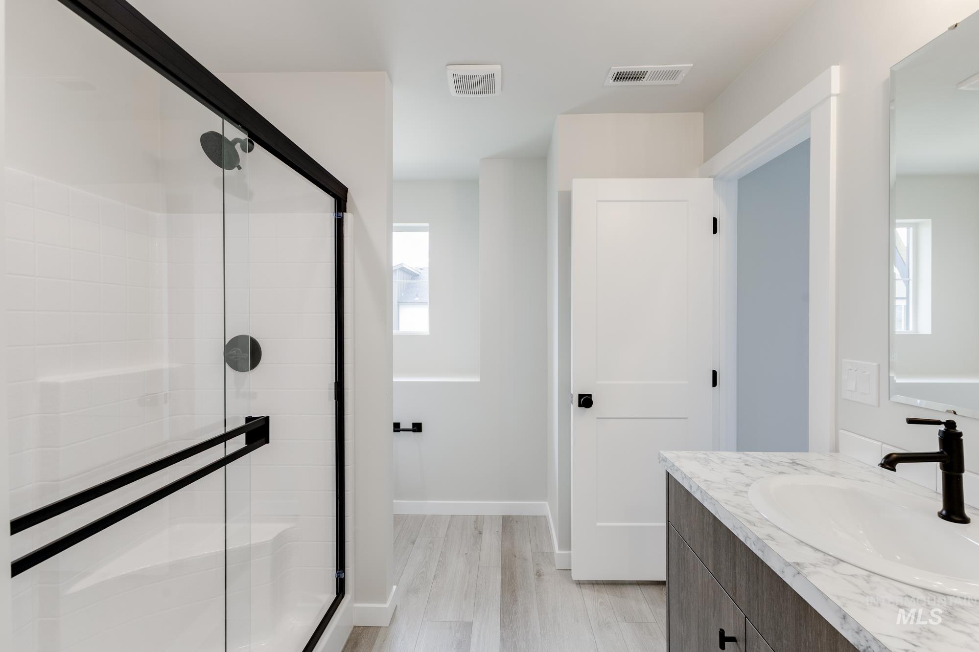 Bathroom with vanity, a shower stall, and light wood-type flooring