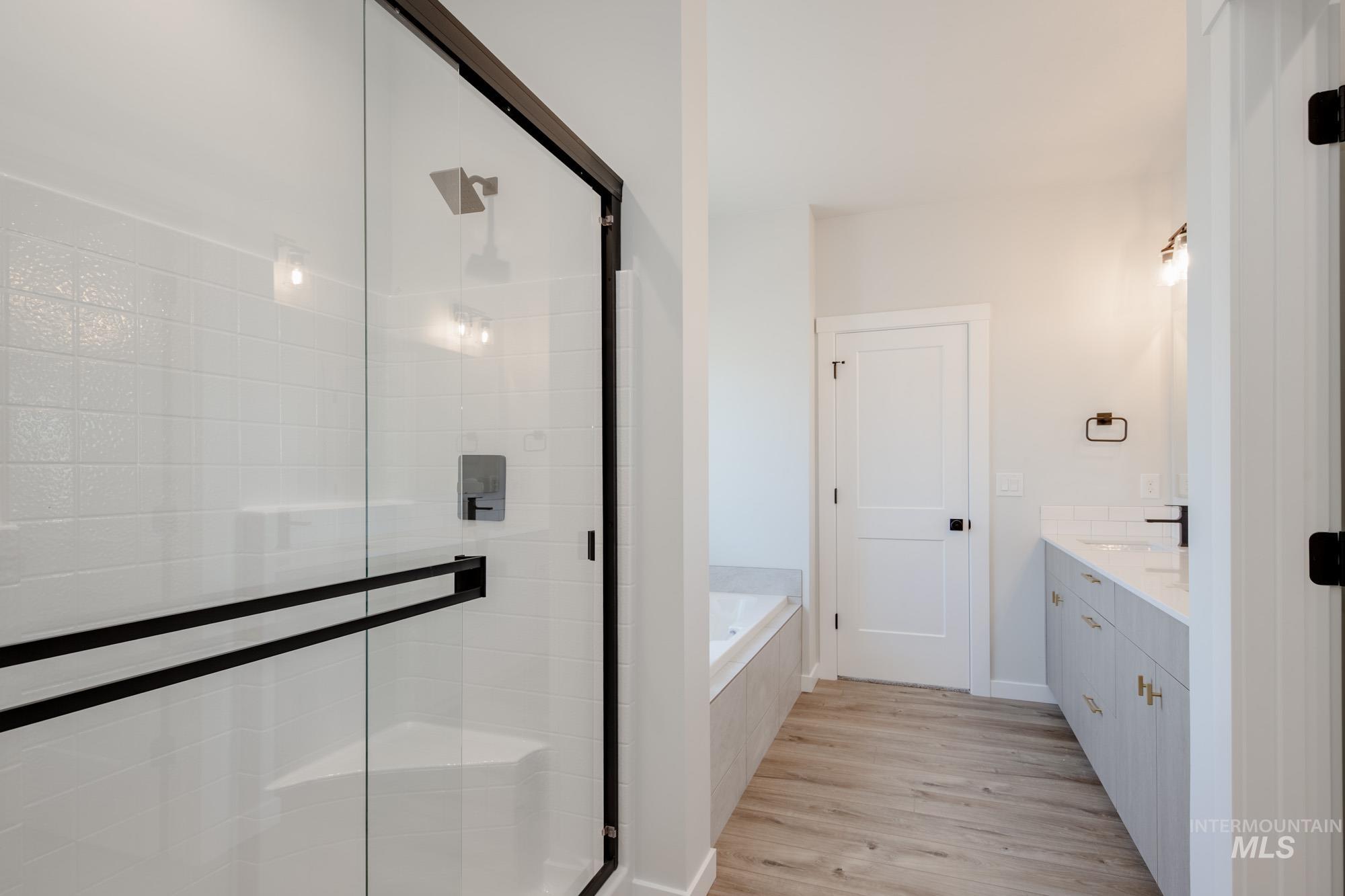 Full bathroom with a stall shower, a garden tub, wood finished floors, and vanity