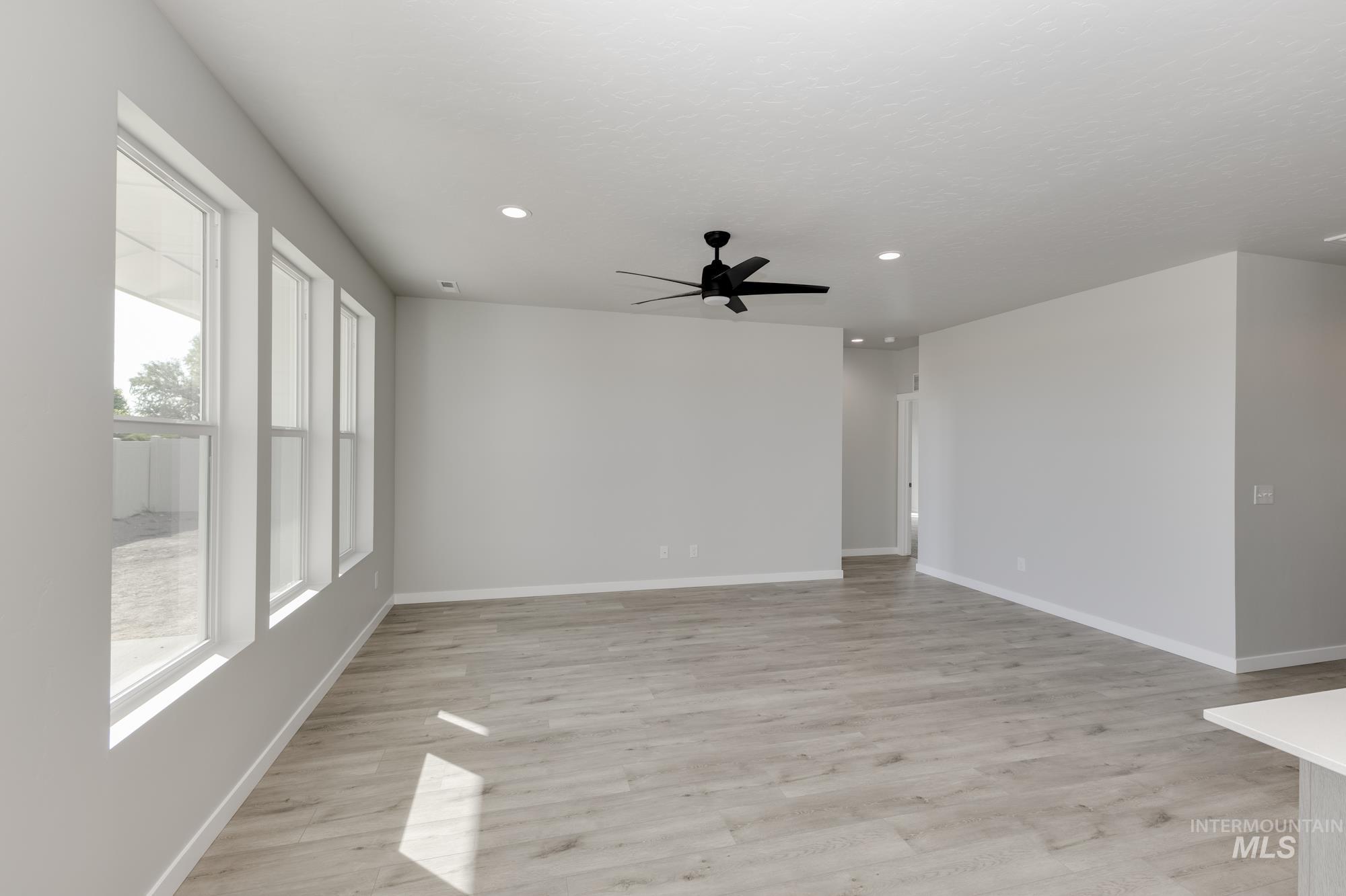 Unfurnished room with healthy amount of natural light, ceiling fan, recessed lighting, and light wood-style flooring