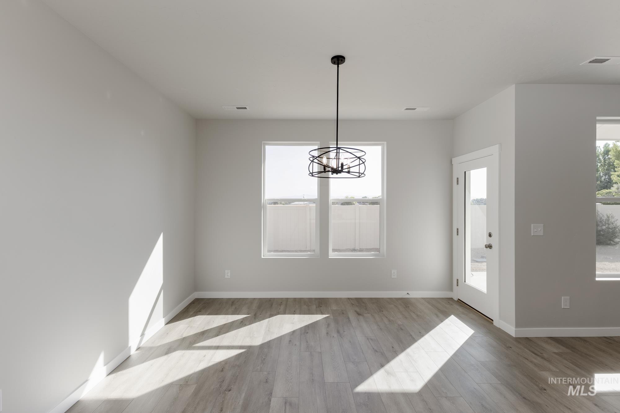 Unfurnished dining area featuring wood finished floors and a chandelier