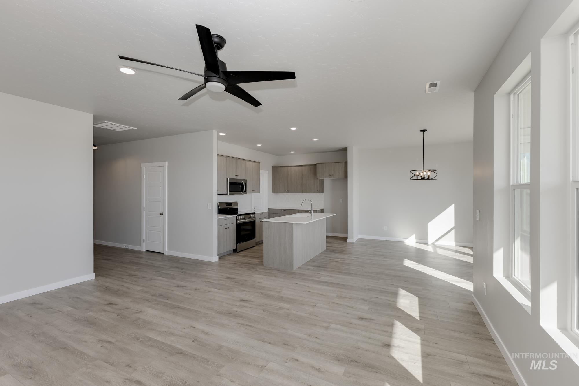 Unfurnished living room with ceiling fan, recessed lighting, light wood-style floors, and a chandelier