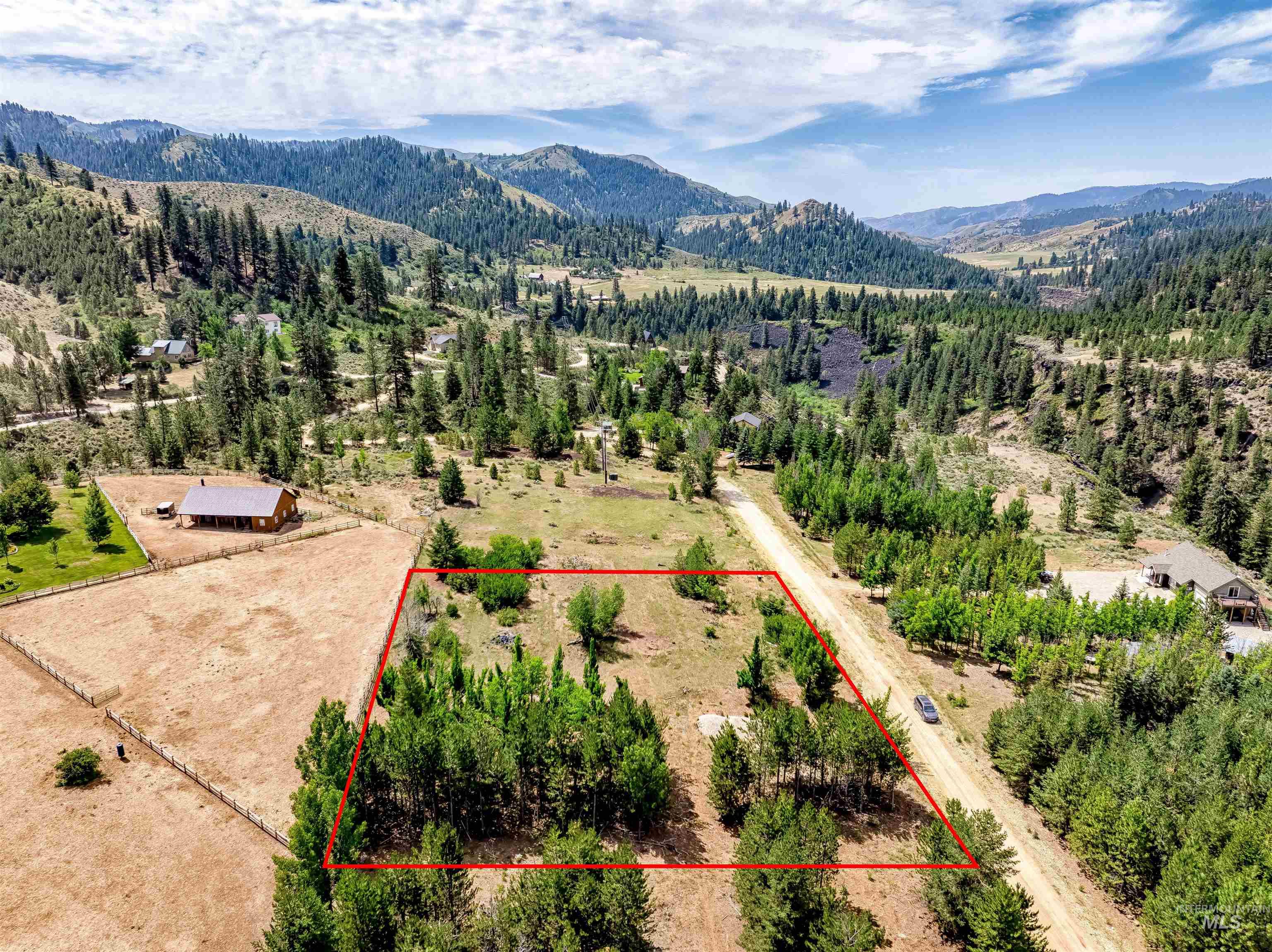 Aerial view of property and surrounding area with a mountainous background and property boundaries highlighted