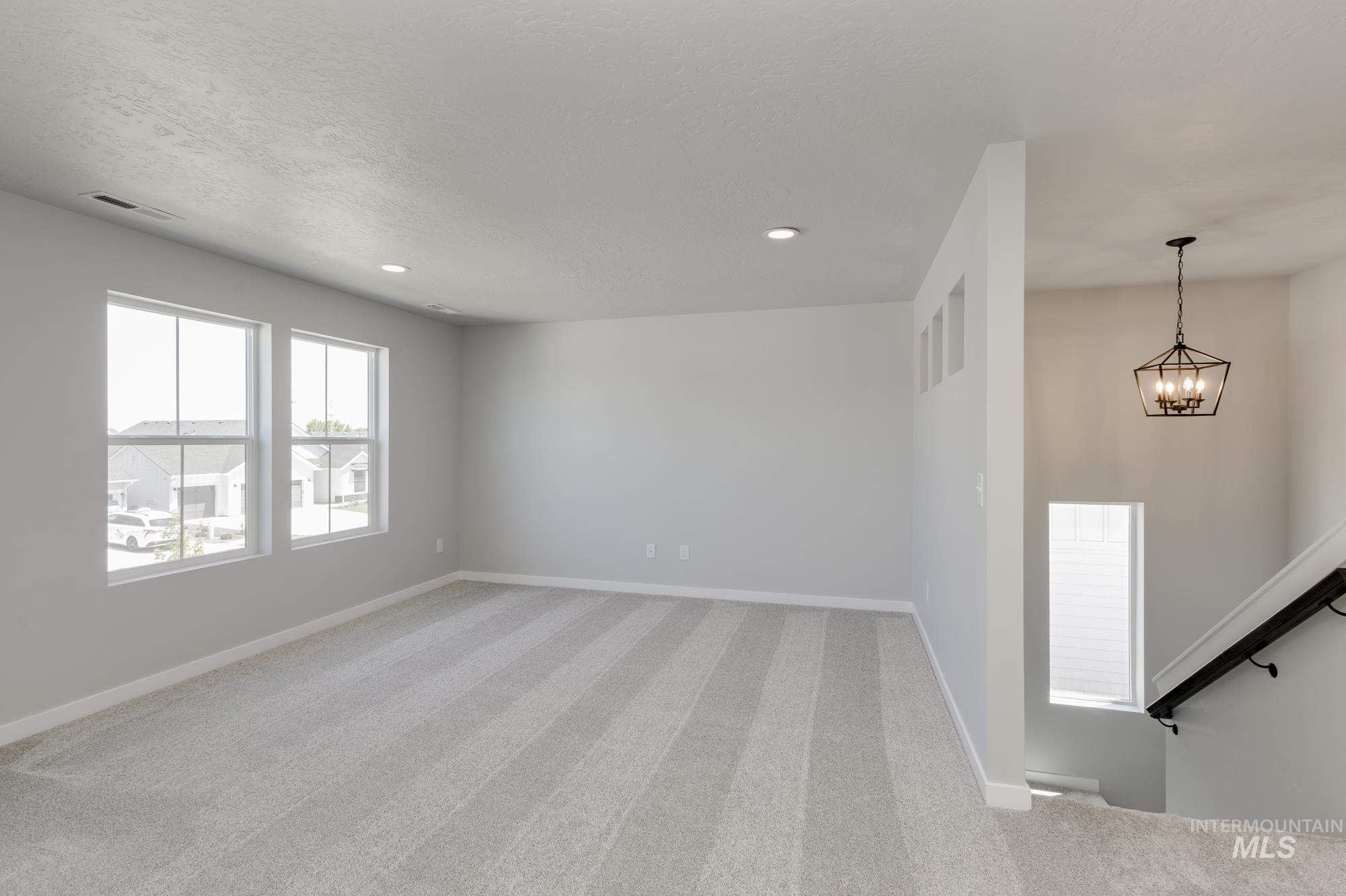 Empty room featuring light colored carpet, a chandelier, and recessed lighting