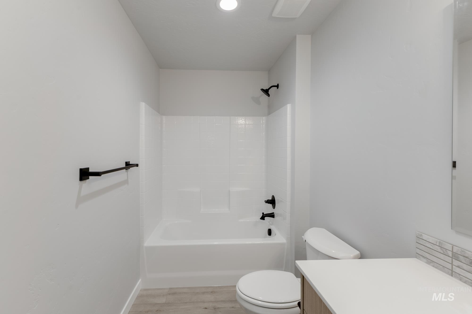 Bathroom with vanity, wood finished floors, and shower / washtub combination