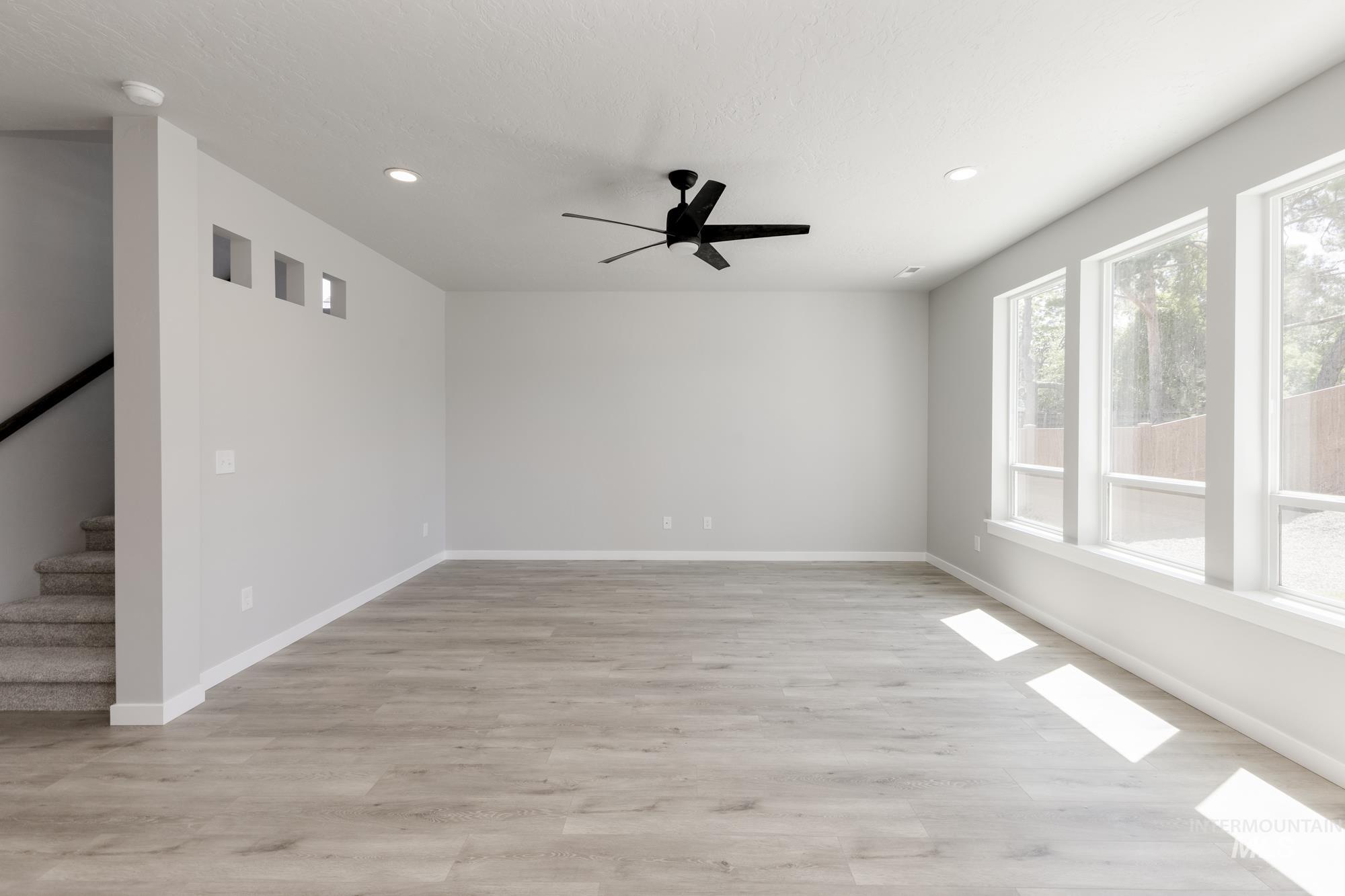 Empty room with recessed lighting, stairs, light wood-style floors, and a ceiling fan