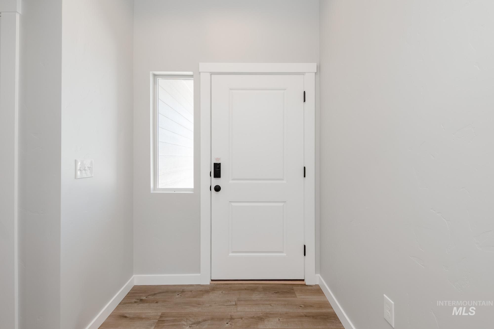 Doorway with light wood-style flooring and baseboards