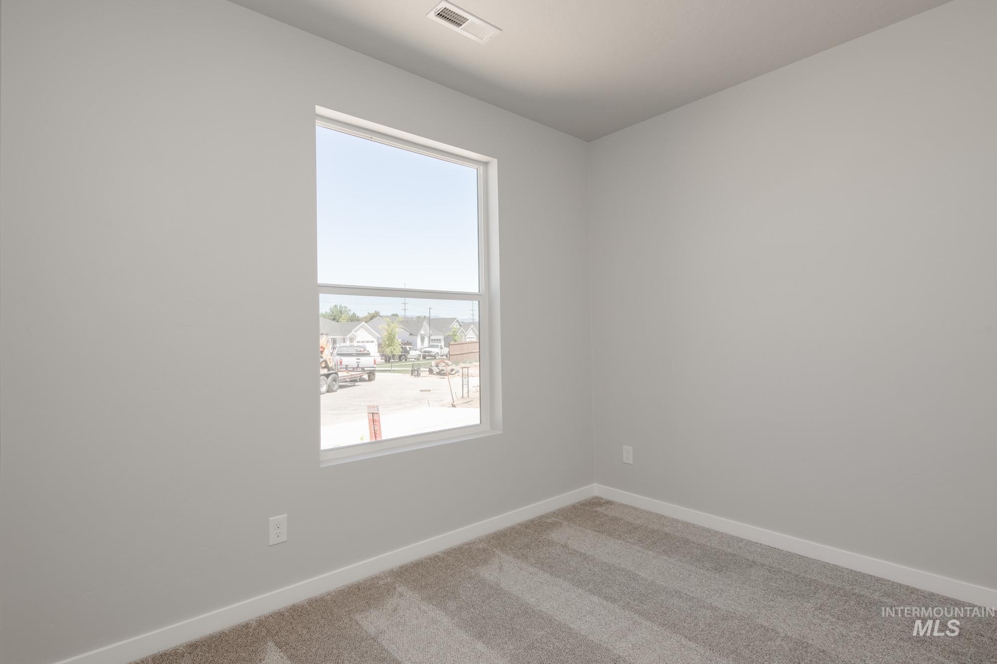 Spare room with baseboards and light colored carpet