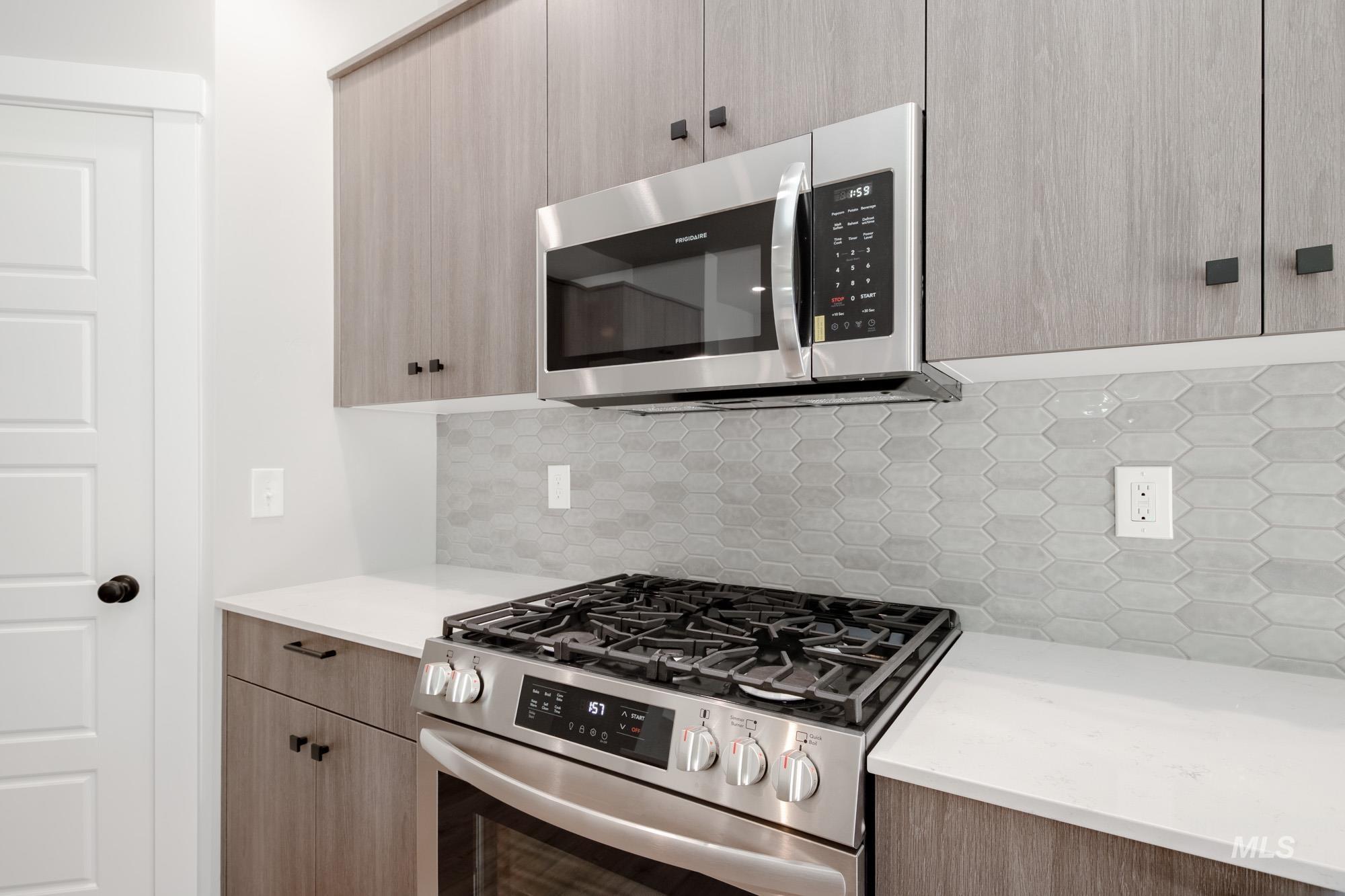 Kitchen with appliances with stainless steel finishes, tasteful backsplash, and light countertops