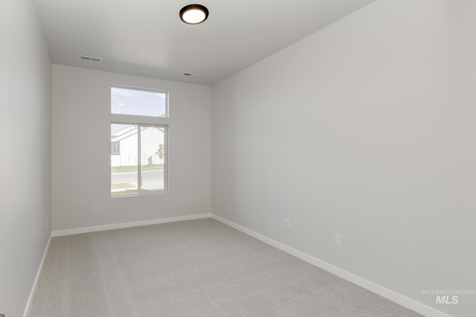 Empty room featuring light carpet and baseboards