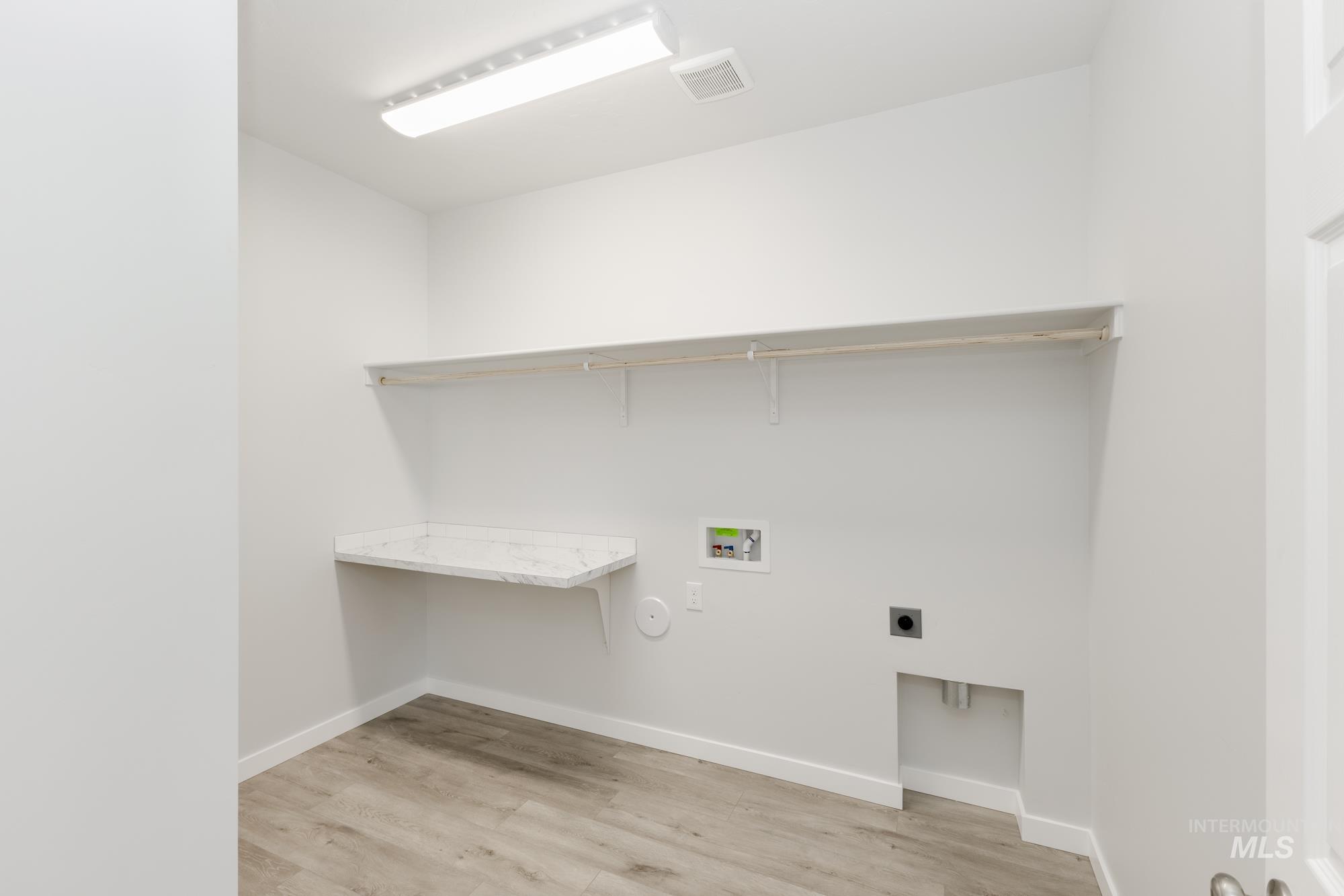 Washroom featuring electric dryer hookup, hookup for a washing machine, and light wood-style floors