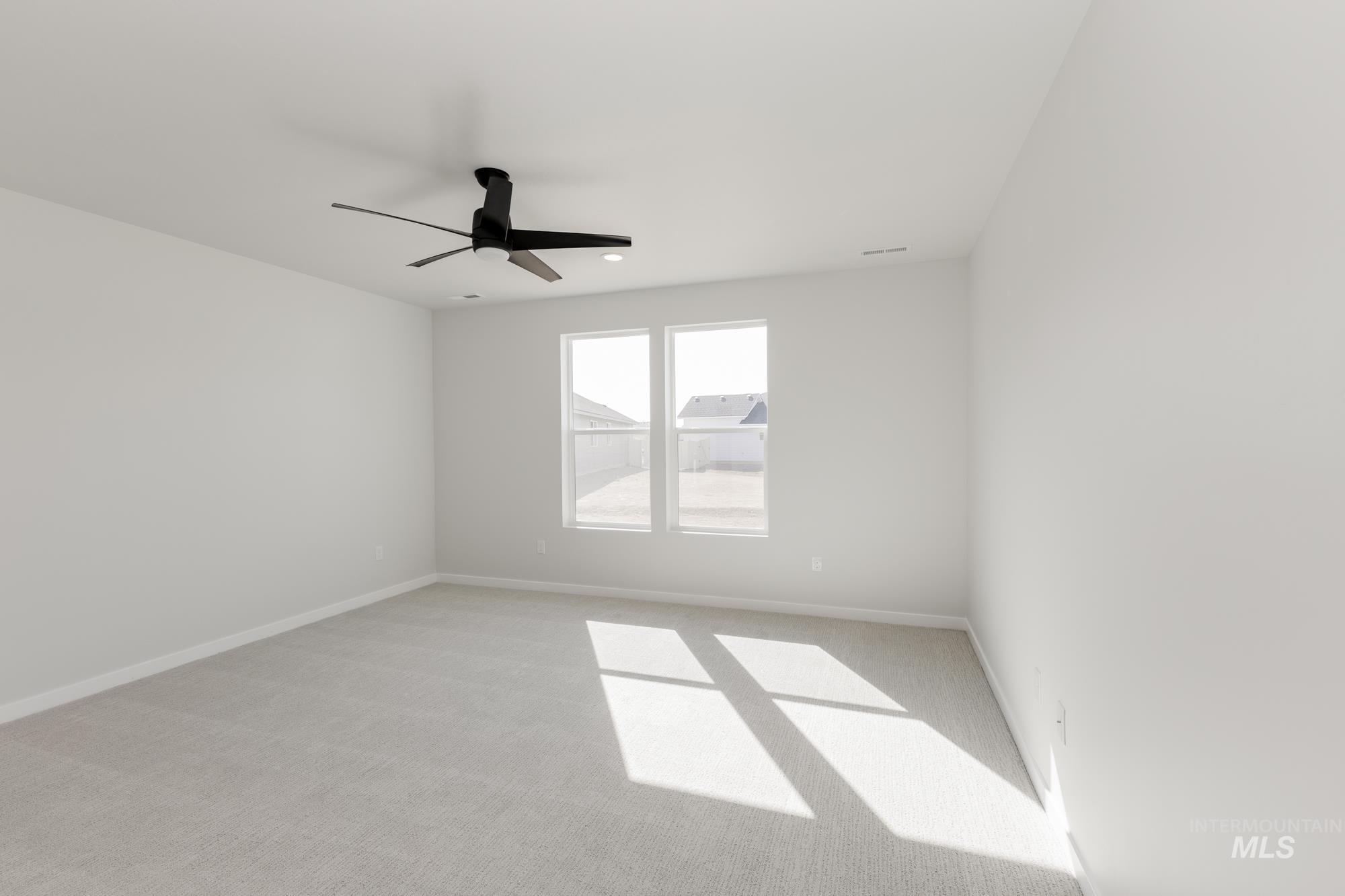 Spare room featuring a ceiling fan and light carpet