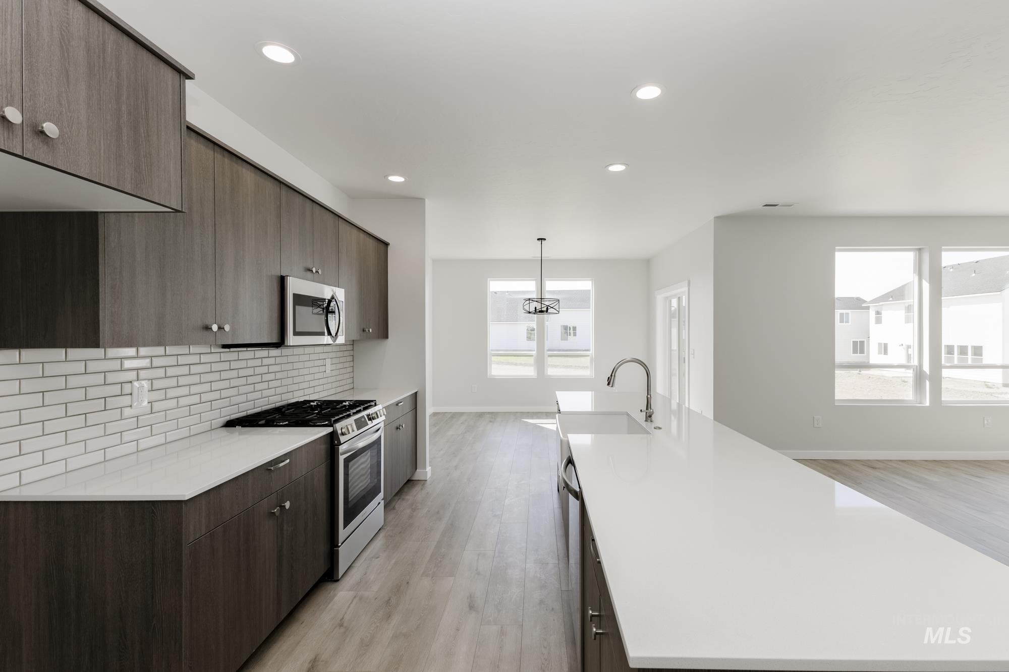 Kitchen featuring stainless steel appliances, a spacious island, light wood finished floors, modern cabinets, and light countertops