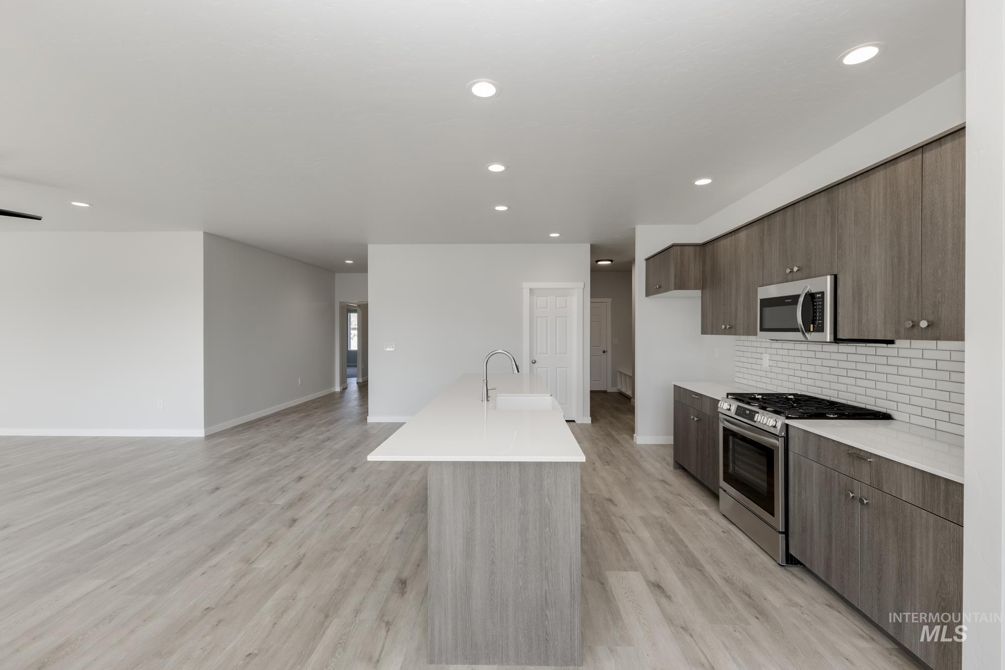 Kitchen featuring stainless steel appliances, modern cabinets, light wood-style floors, backsplash, and recessed lighting
